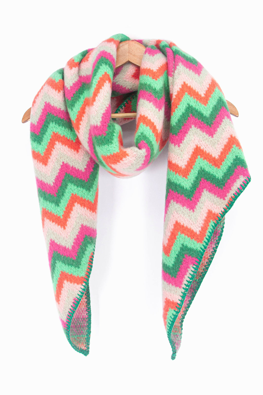 showing the multicoloured green, pink, orange and beige zig zag pattern winter scarf draped around a coat hanger, showing how it would look when worn.
