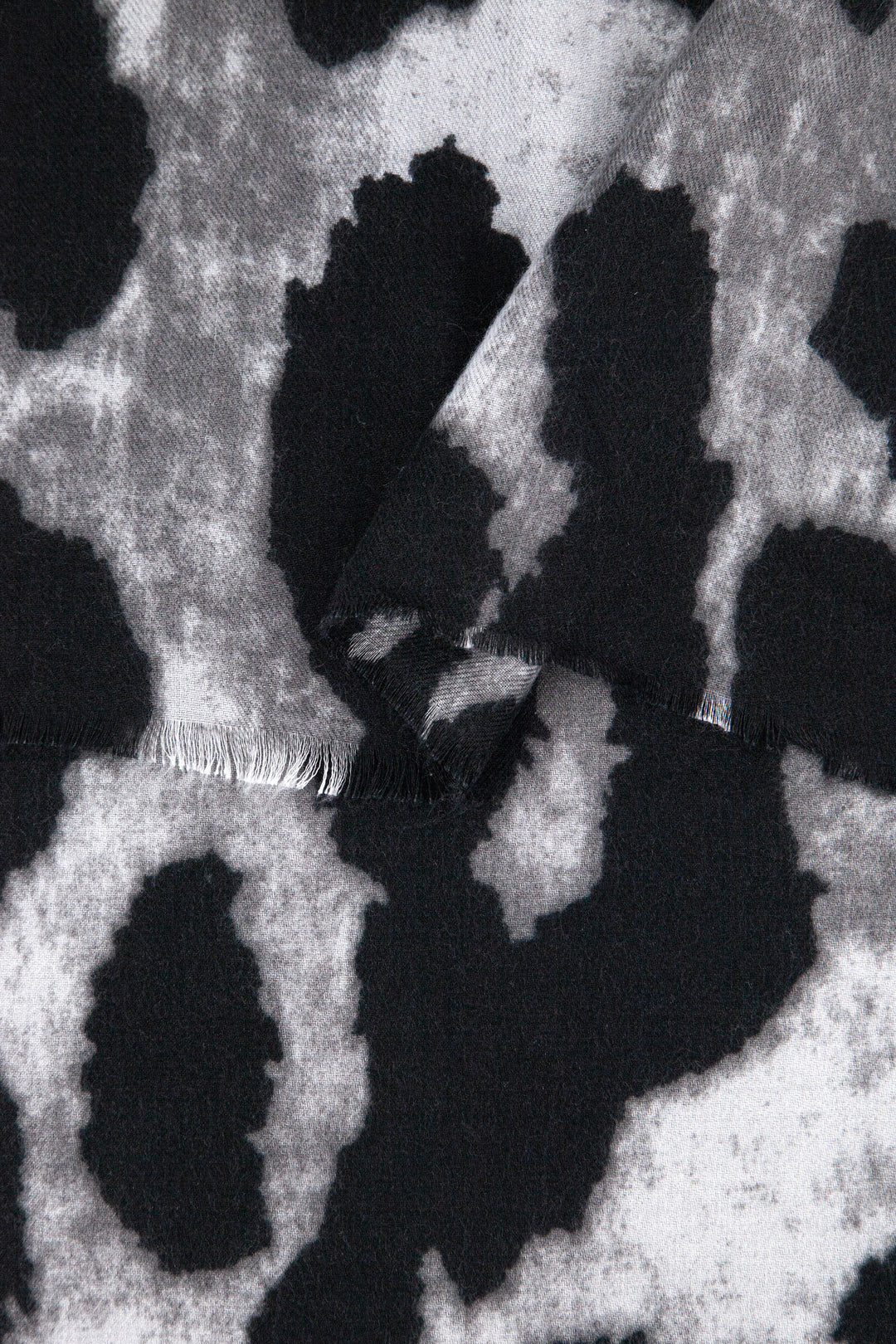 close up of the soft viscose fabric, the black and grey large leopard print design is clearly visible