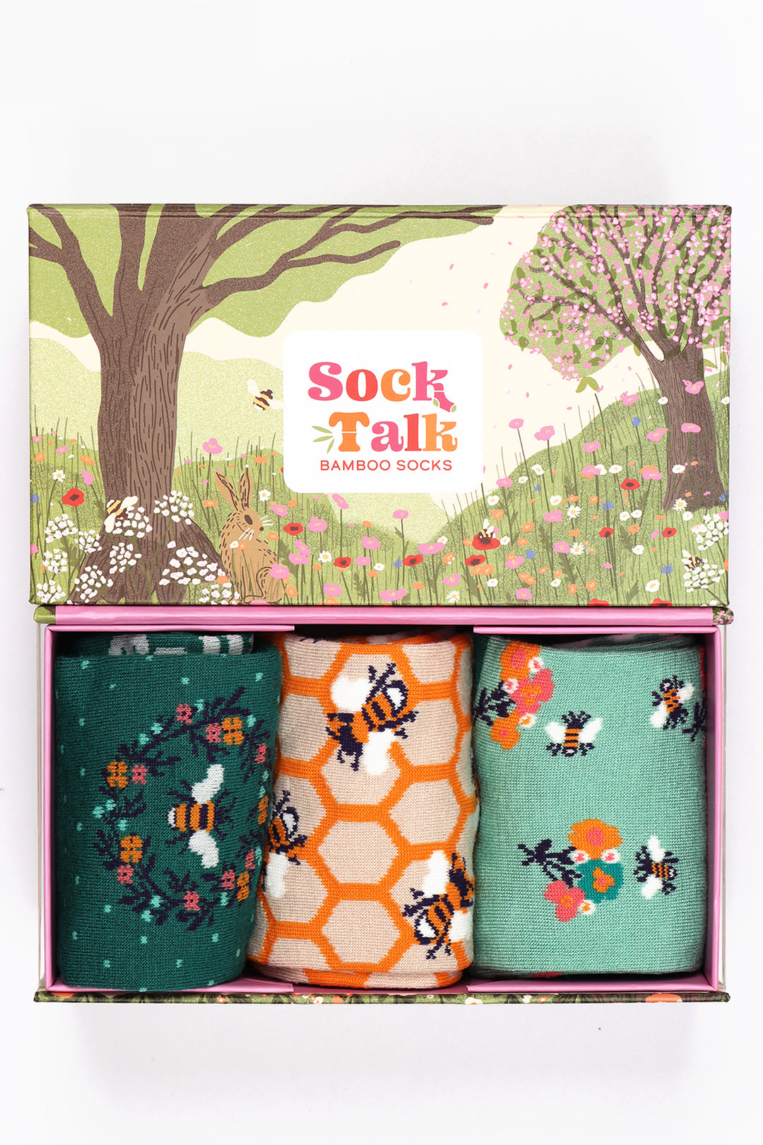 an artistic gift box designed to look like a summer meadow with wild flowers,  cherry blossom trees and rolling hills with three pairs of ladies bamboo socks featuring bees and flowers