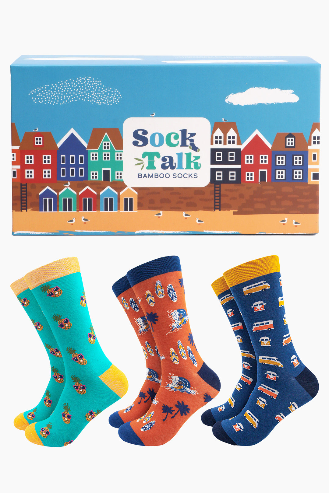 an artistically designed gift box which looks like a beach front with colourful houses, sandy shore and beach huts and three pairs of mens bamboo socks featuring tropical pineapples, campervans and surf boards
