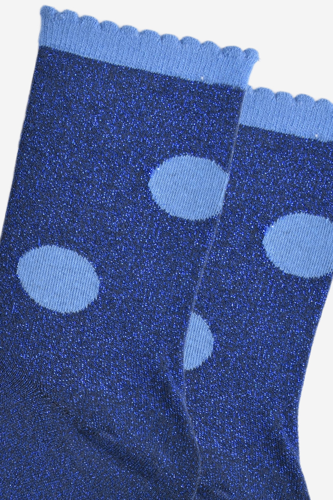 close up of the blue polka dot pattern on the socks. the blue polka dots are a light blue and contrast the royal blue glitter background of the socks