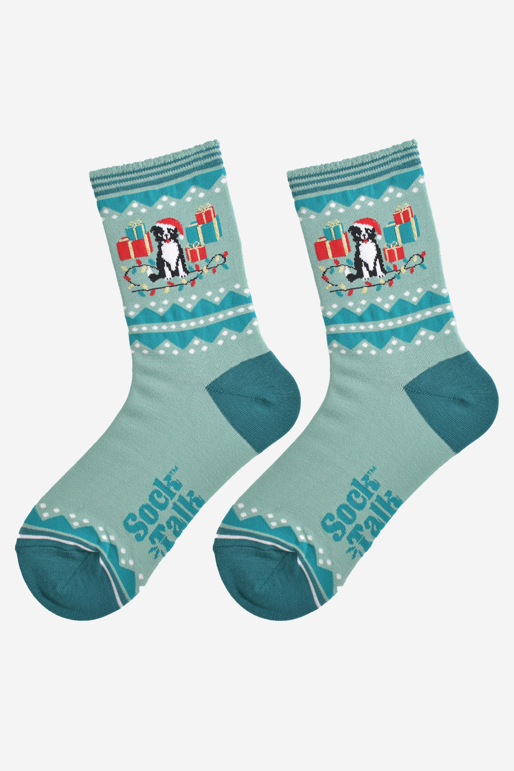 showing the border collie socks laying flat, they are mint and sage green , the dog on the ankles is sitting amongst a pile of red and green xmas gifts and colourful party lights
