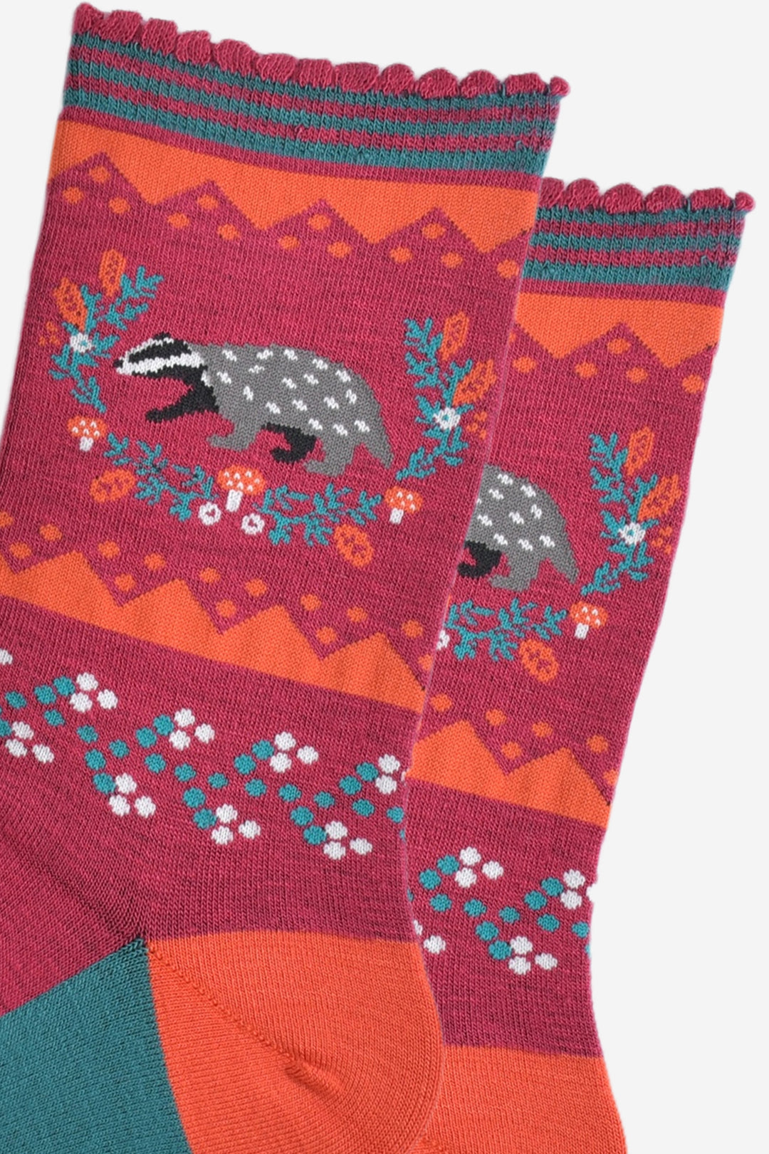 close up of the badger and wreath on the ankle of the socks, the badger is grey and black and the wreath is freen with red toadstool and autumn leaf accents