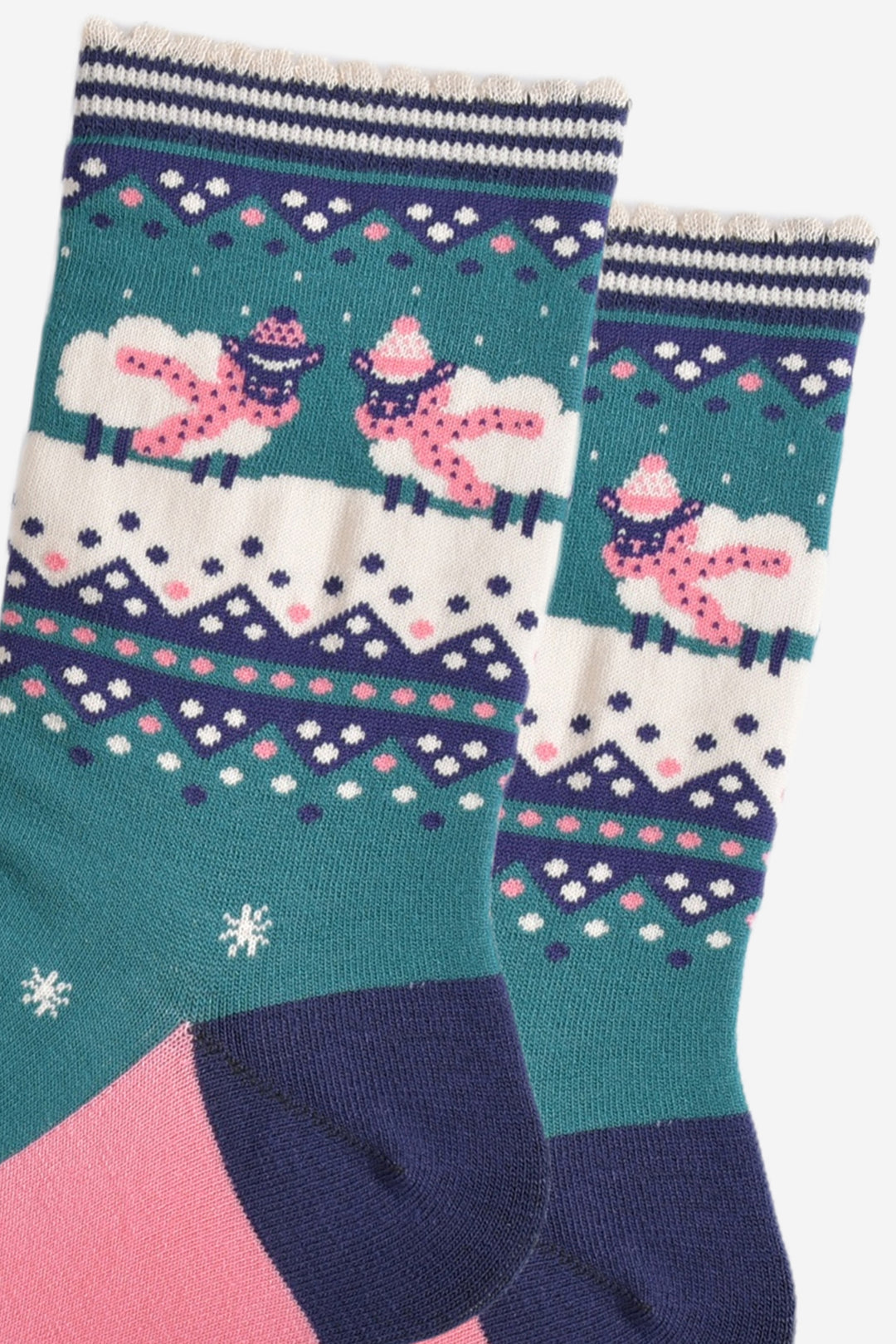close up of the sheep design on the ankle of the socks, there are two sheep standing in snow, each wearing pink hats and winter scarves