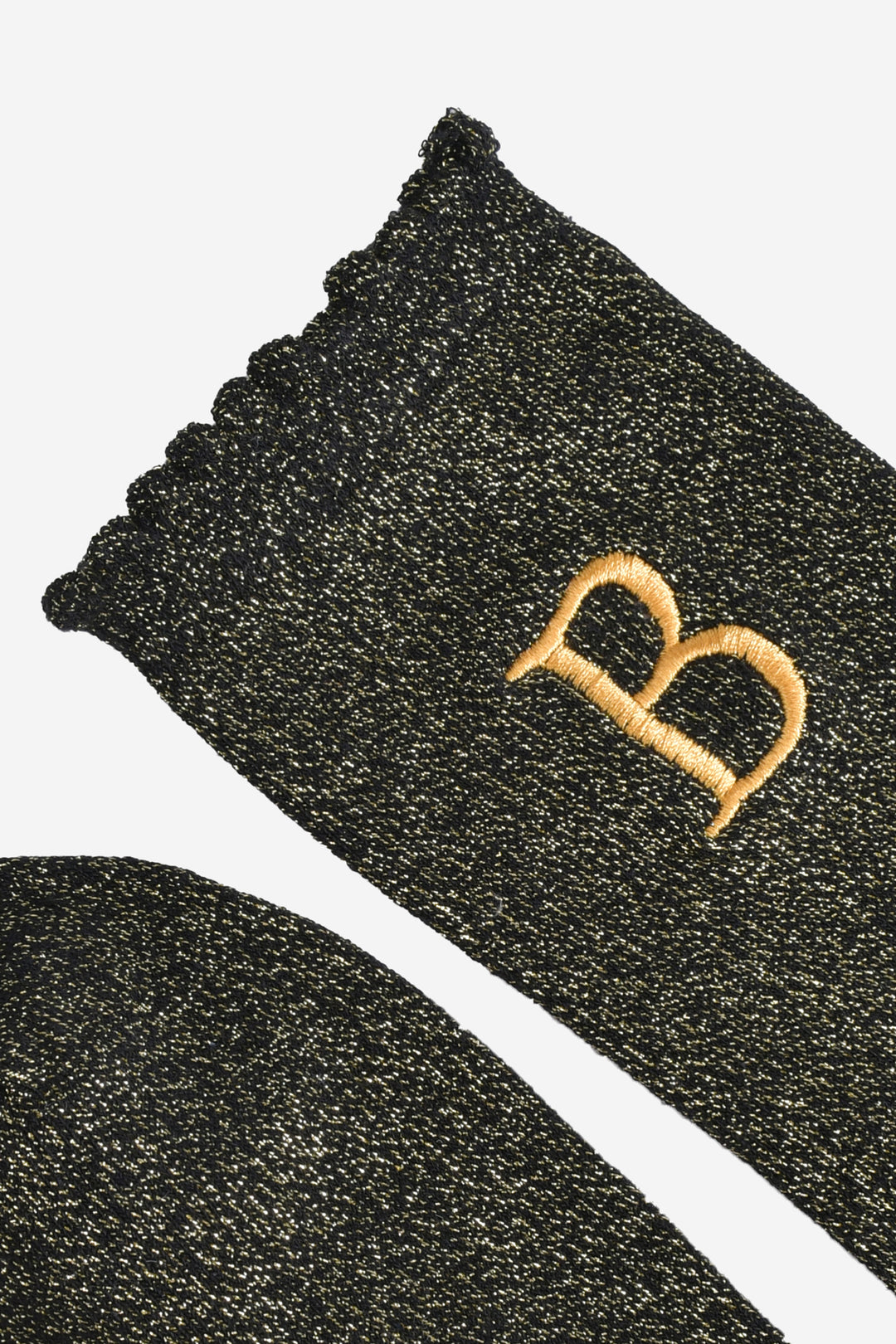 close up of the scalloped cuff on the socks, the toe is the same black and gold as the rest of the socks