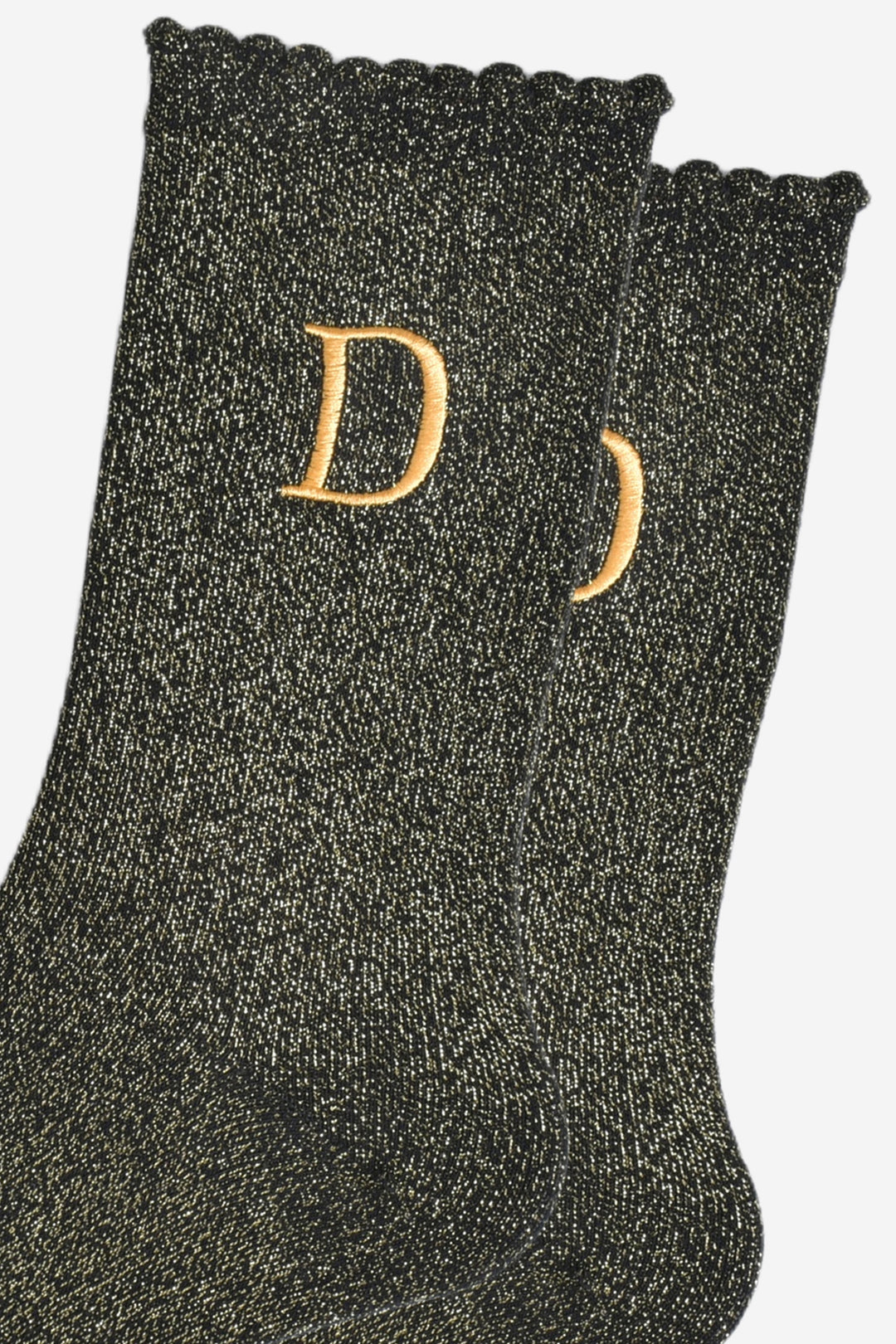 close up of the gold embroidered capital letter d on the ankle of the socks
