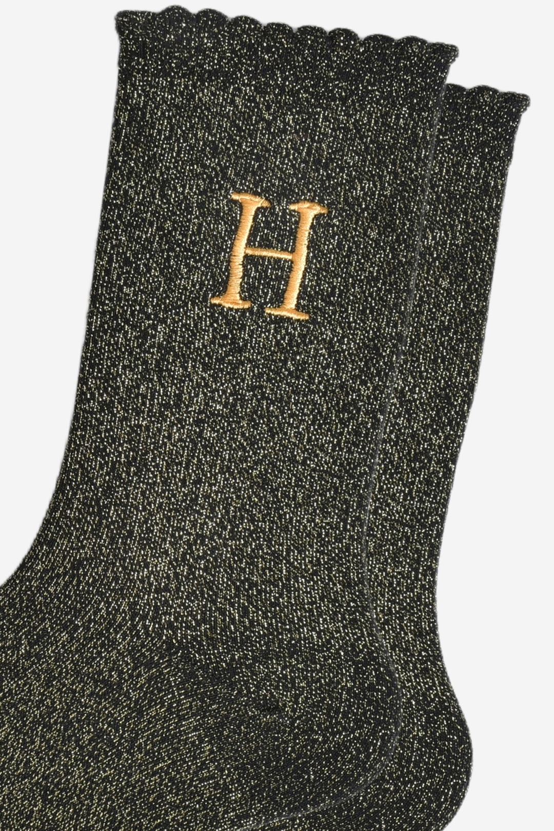close up of the gold embroidered capital letter h on the ankle of the socks