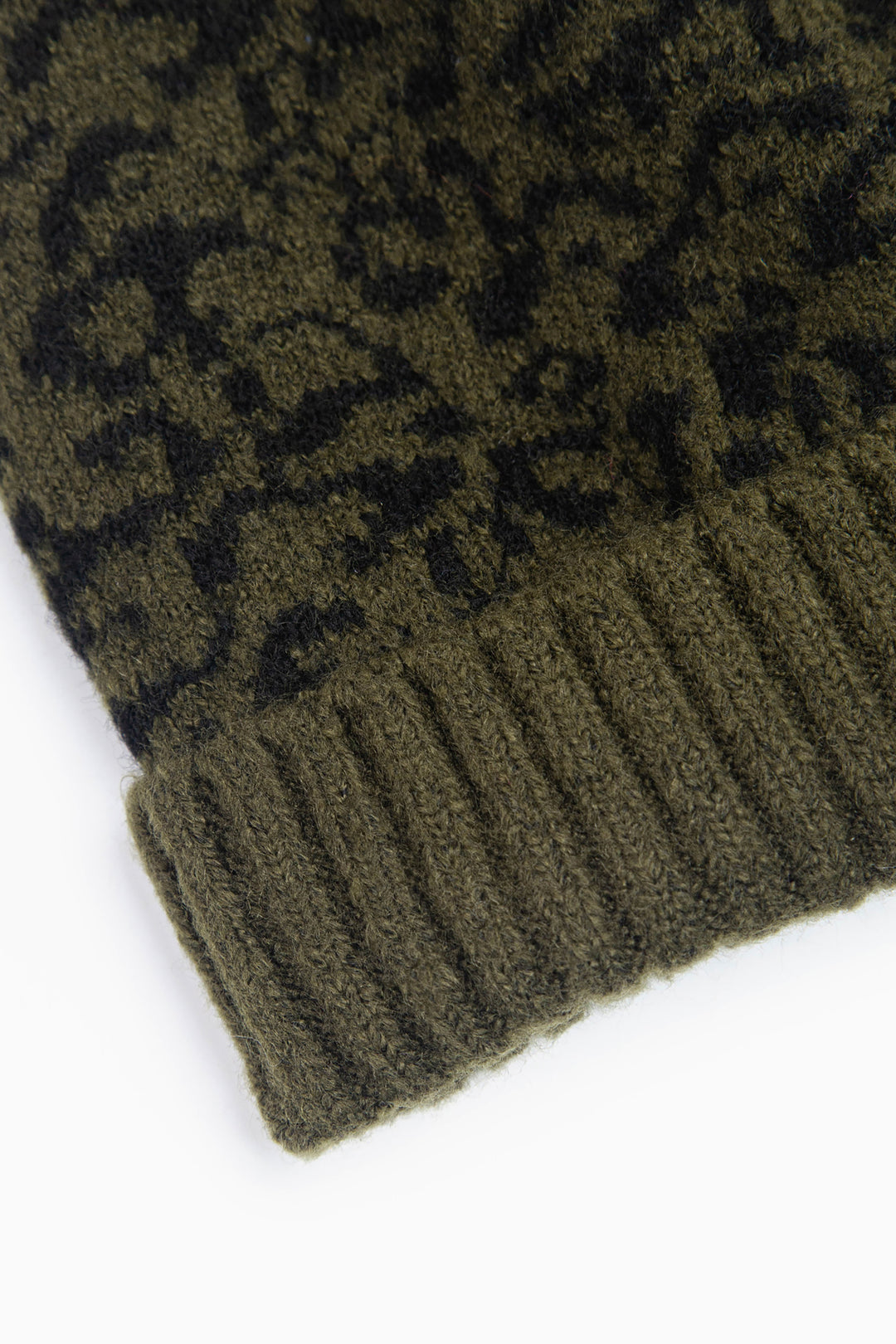 close up of the ribbed brim on the beanie hat, it is plain khaki green in contrast to the main patterned design of the rest of the hat.