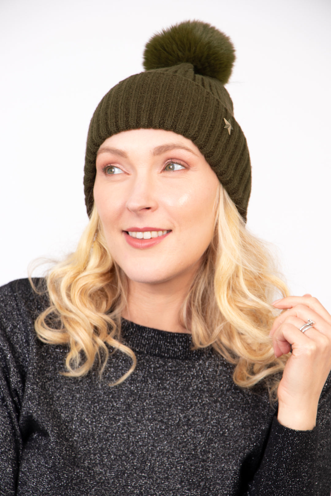 model wearing a khaki coloured knitted ribbed beanie hat with a pom pom on top and a gold metallic star on the brim.