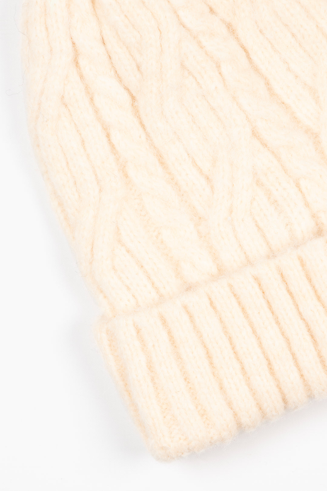 close up of the ribbed brim of the beanie hat and of the cable knit pattern.