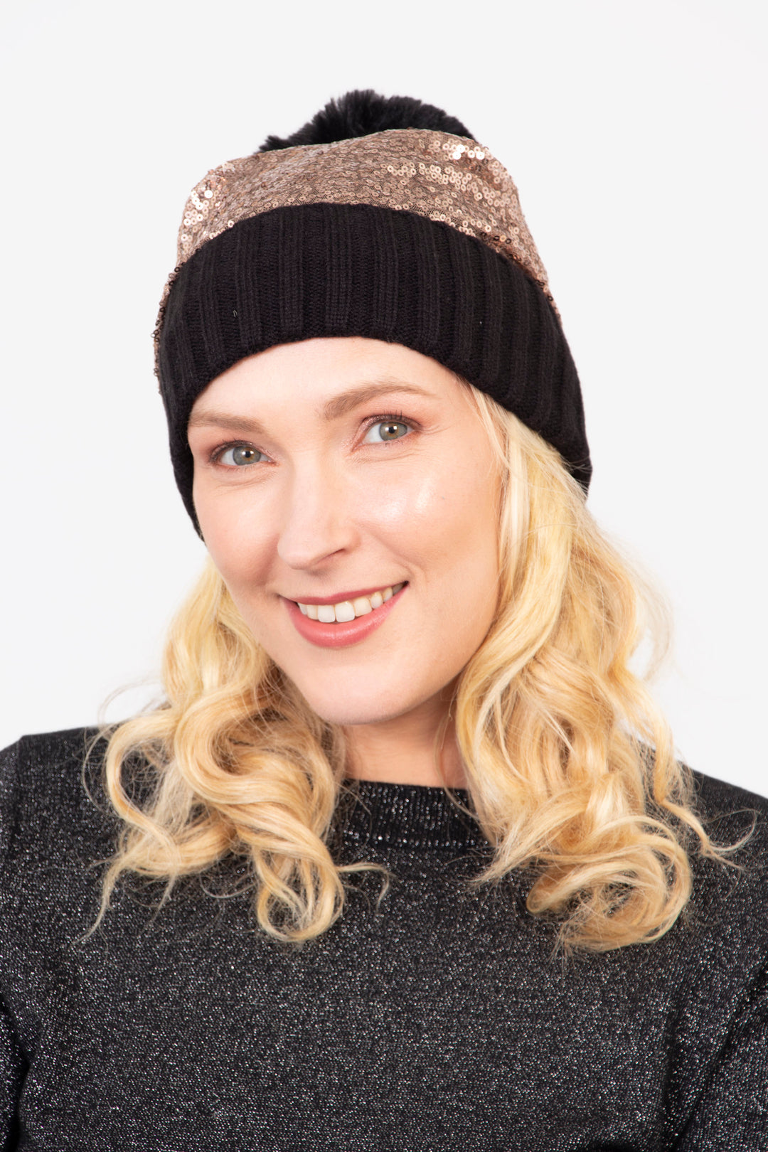 model wearing a black hat with a pom pom and bronze sequin