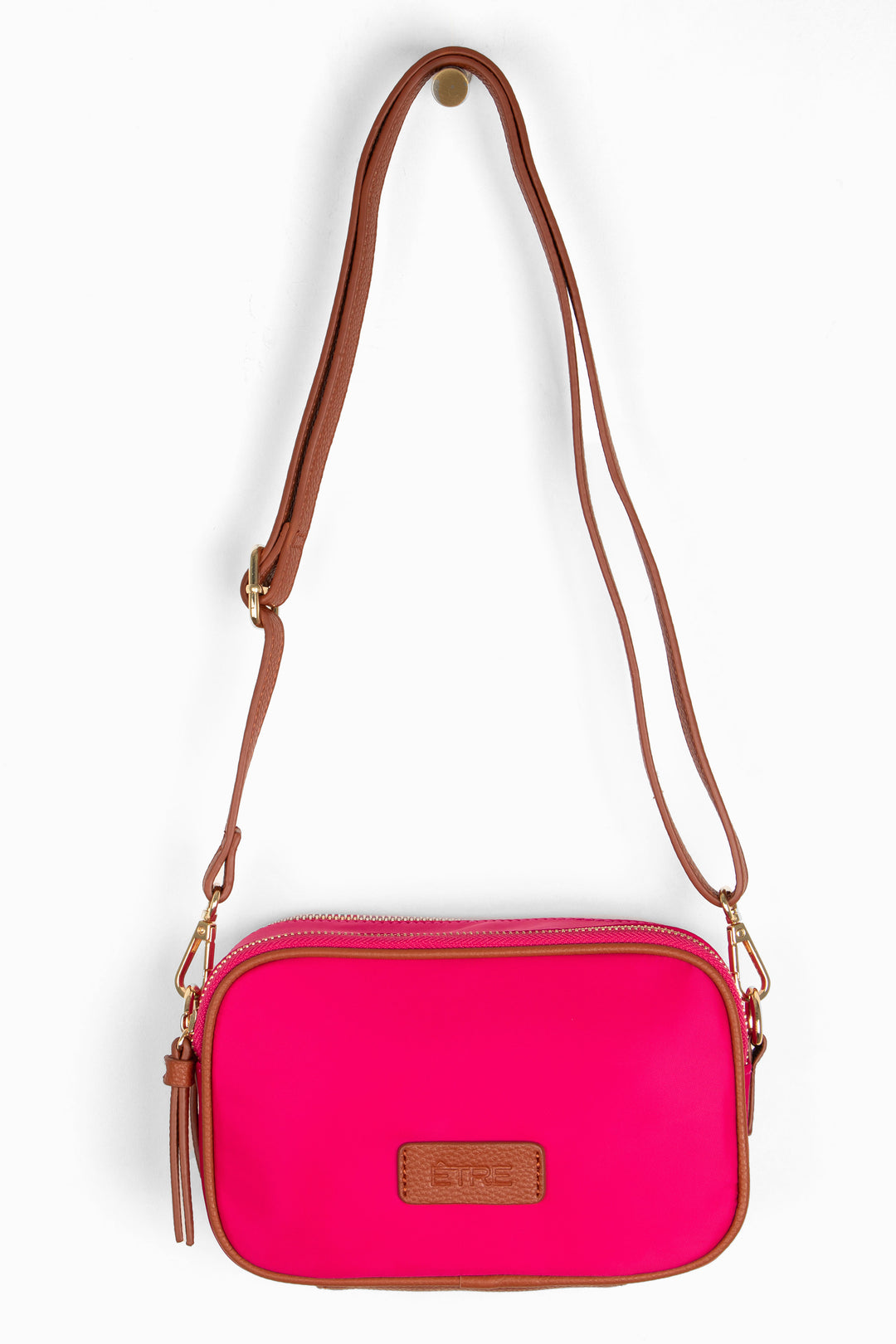 fuchsia pink crossbody bag with tan faux leather accents and a detachable strap