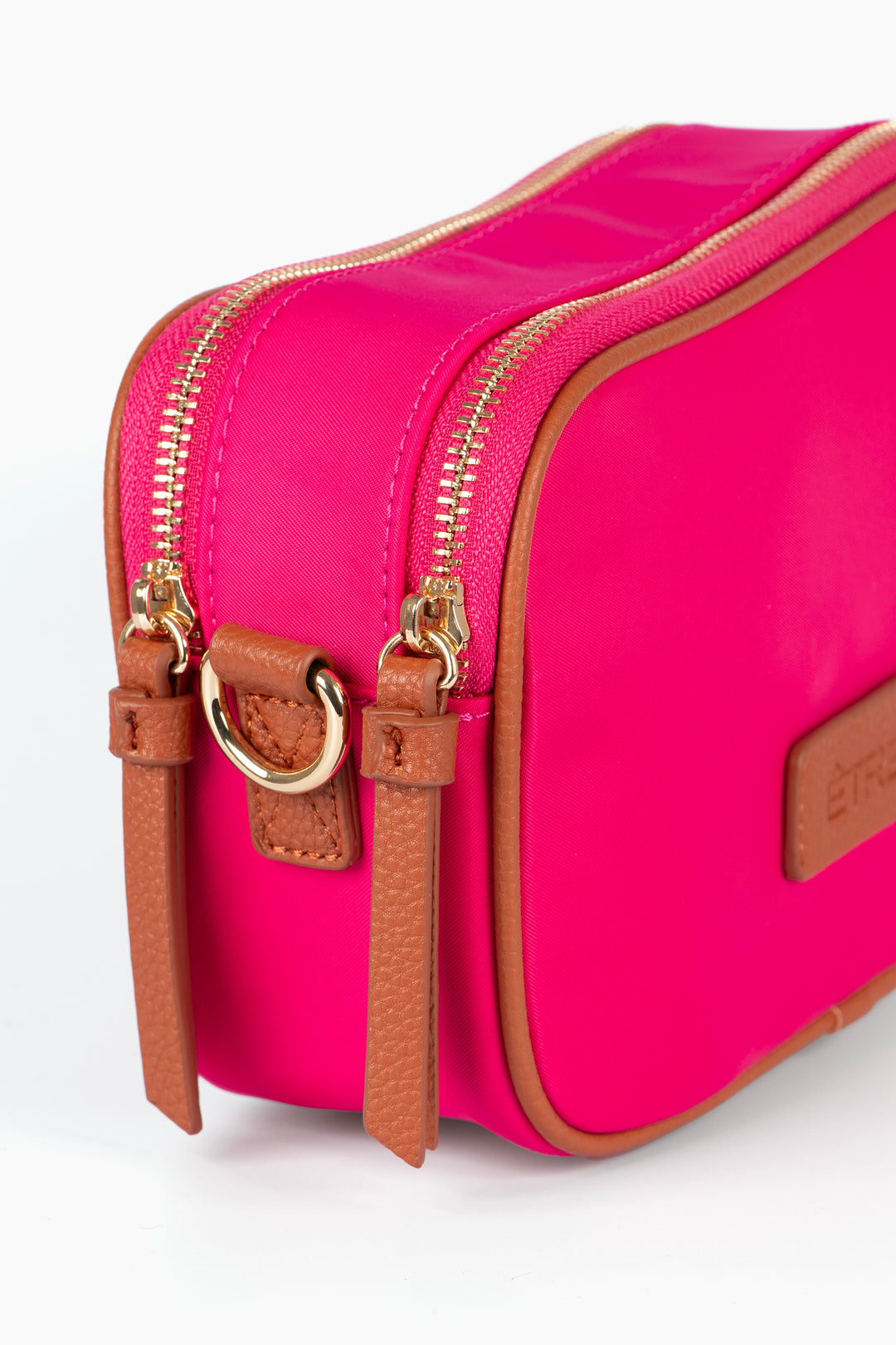 close up of the end of the bag, showing clearly the twin zip fastening compartments, There are two gold zips on the top of the bag each with tan faux leather tabs