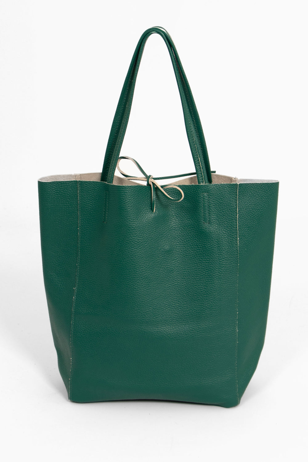 emerald green leather tote bag standing upright. the top tie fastening is  in the centre of the top of the bag. the handles are thin.