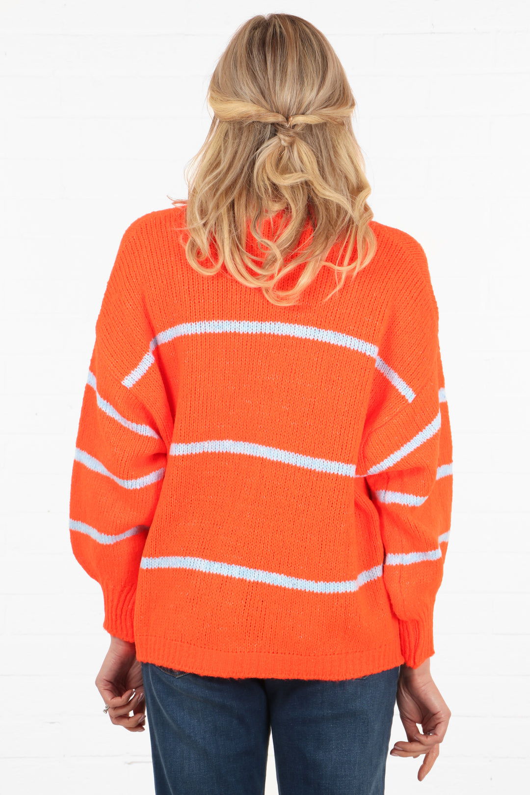 model showing the back of the orange cardigan, showing that the back has three white stripes