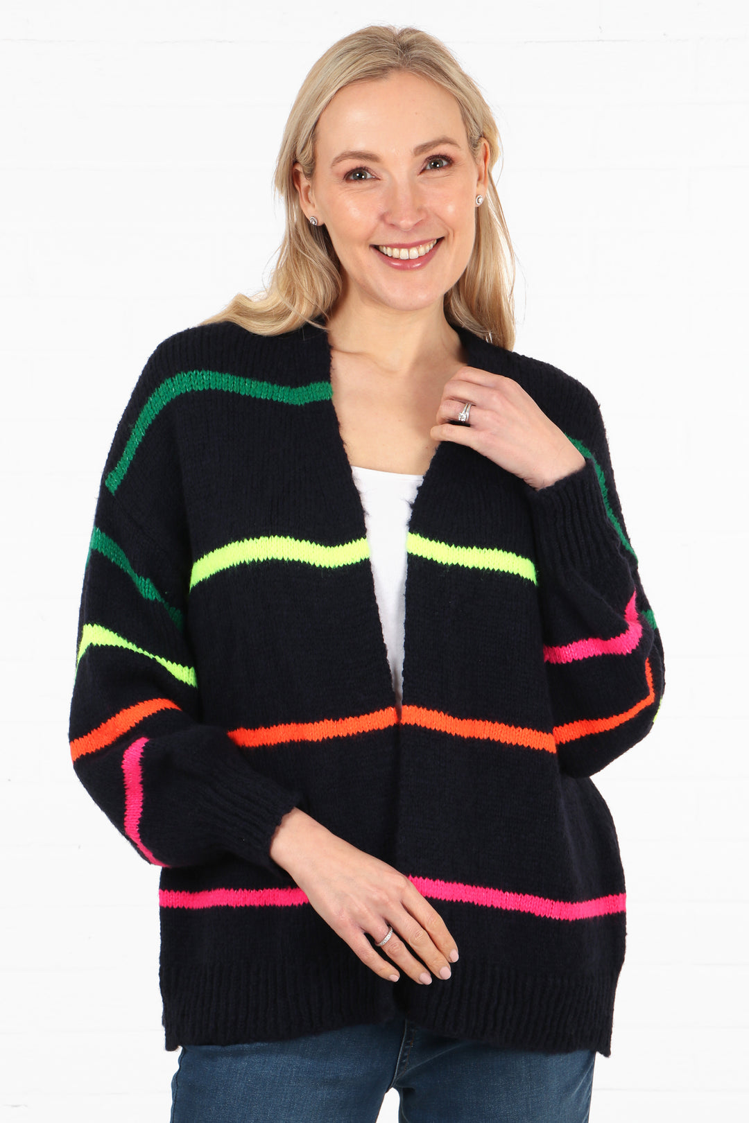 model wearing a navy blue open front knitted cardigan with thin multicoloured stripes throughout