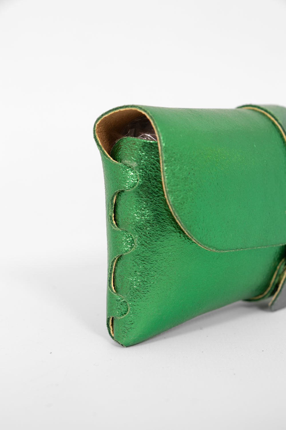 close up of the side view of the sunglasses case, showing the structure of the design. the case has a folding front which is secured by a button fastening