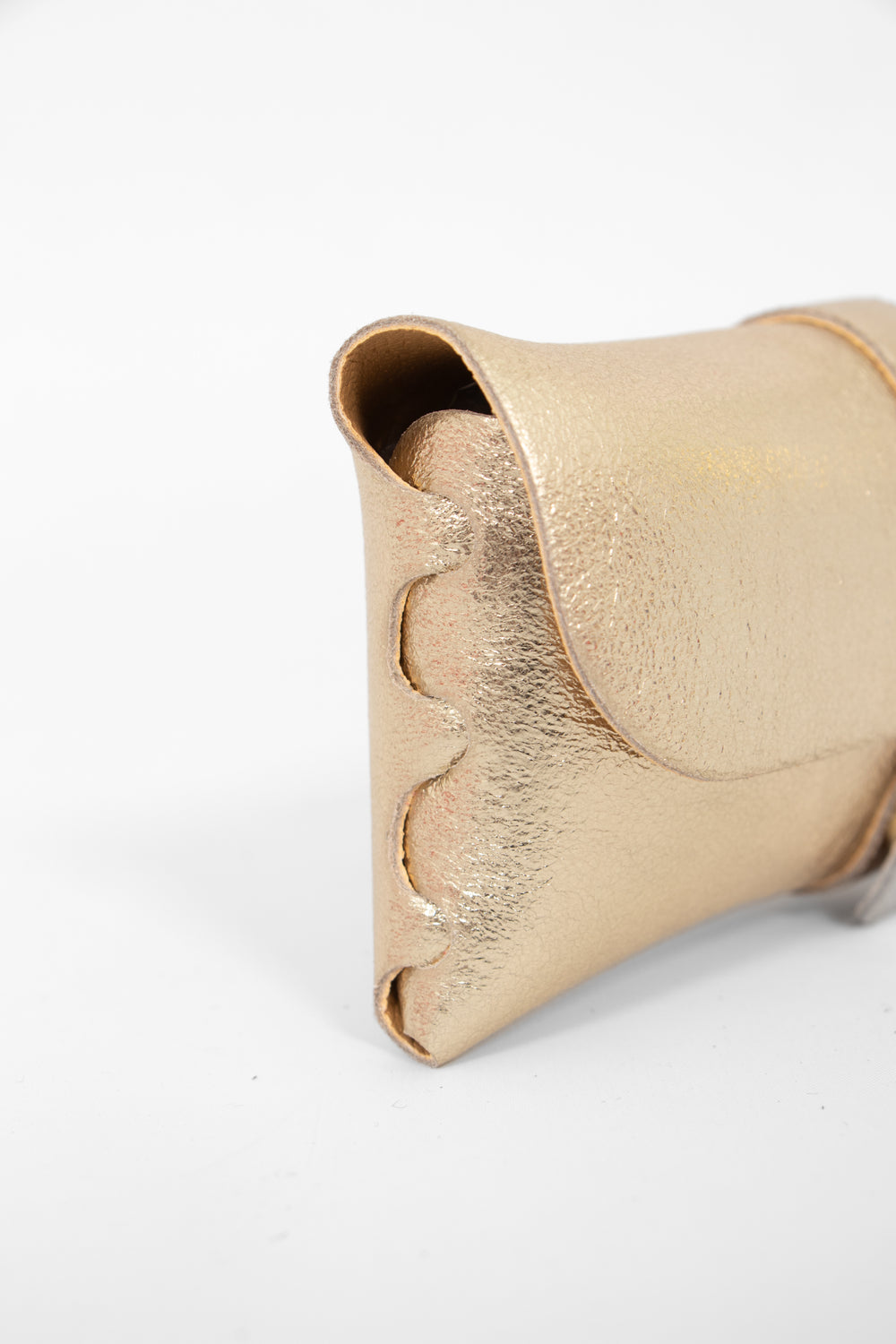 close up of the side view of the sunglasses case, showing the structure of the design. the case has a folding front which is secured by a button fastening