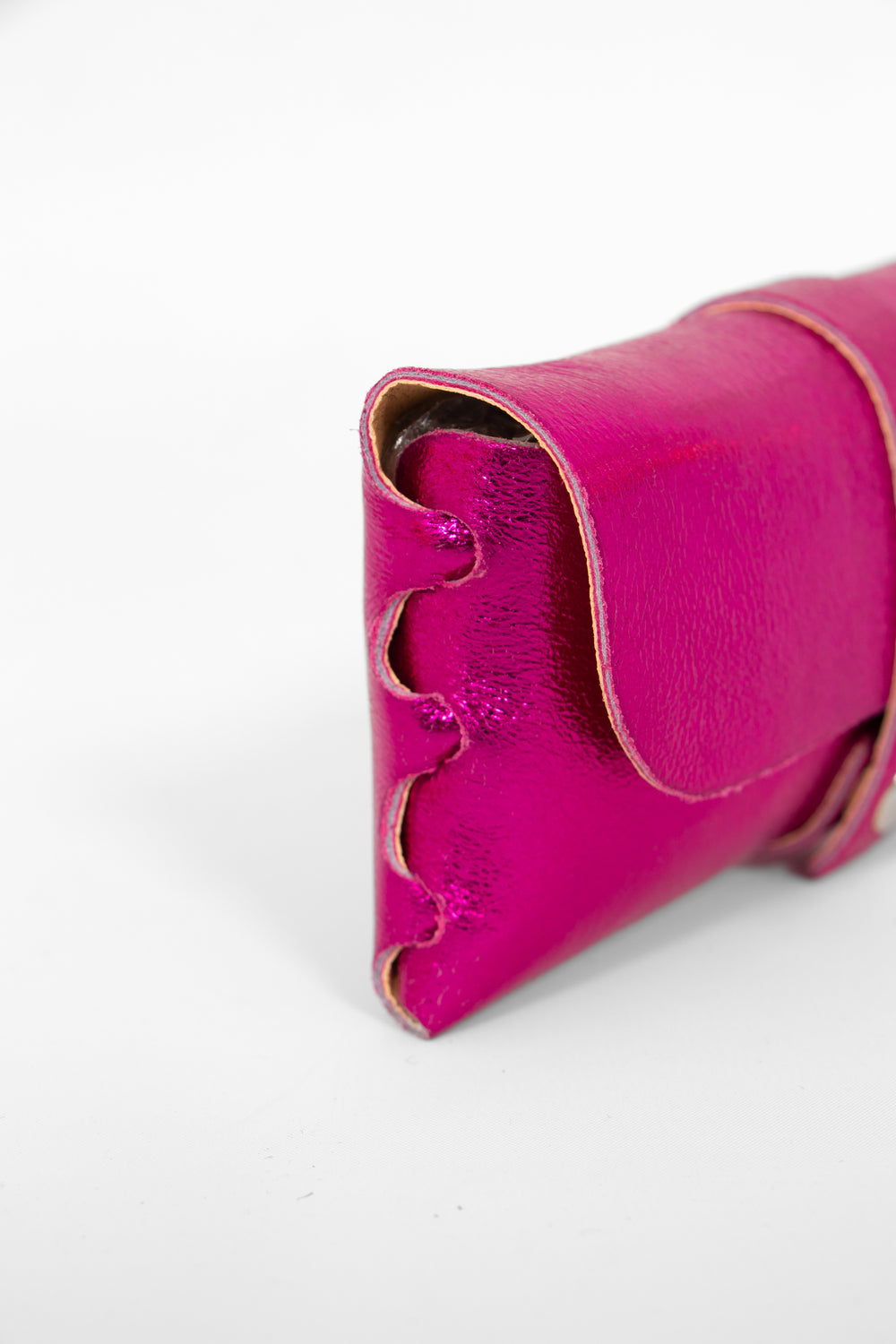 close up of the side view of the sunglasses case, showing the structure of the design. the case has a folding front which is secured by a button fastening