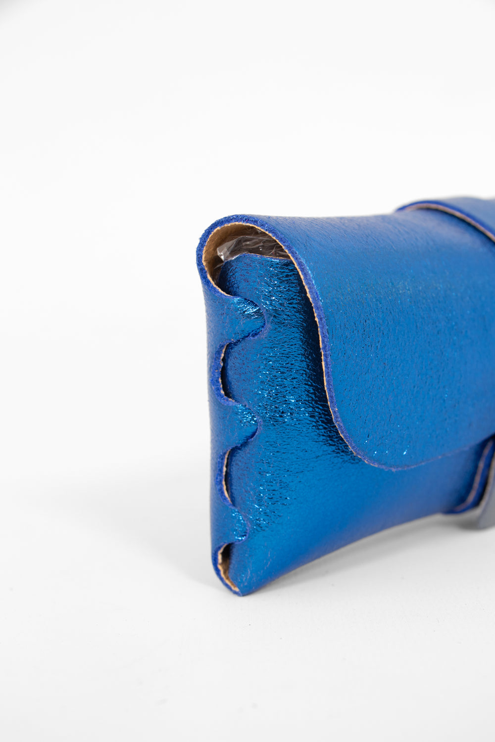 close up of the side view of the sunglasses case, showing the structure of the design. the case has a folding front which is secured by a button fastening