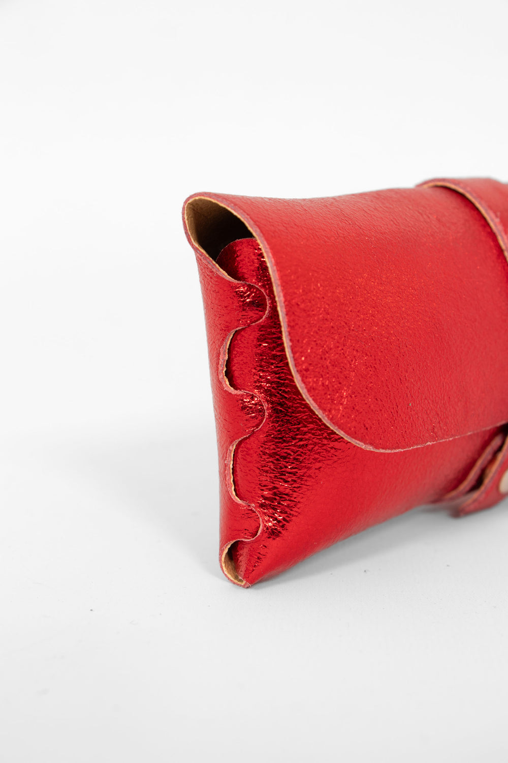 close up of the side view of the sunglasses case, showing the structure of the design. the case has a folding front which is secured by a button fastening