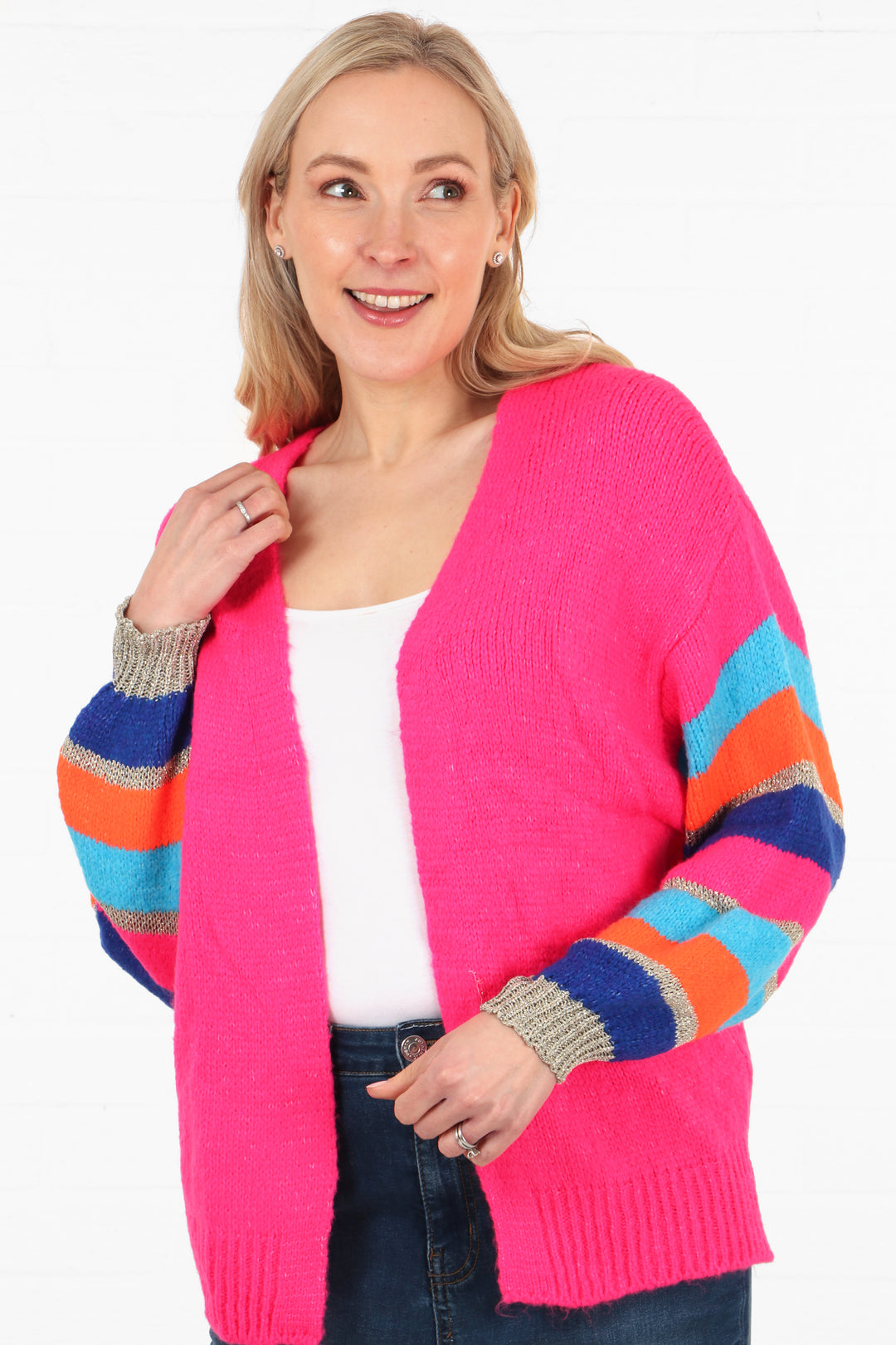 model wearing a short open front pink knit cardigan with multicoloured striped sleeves