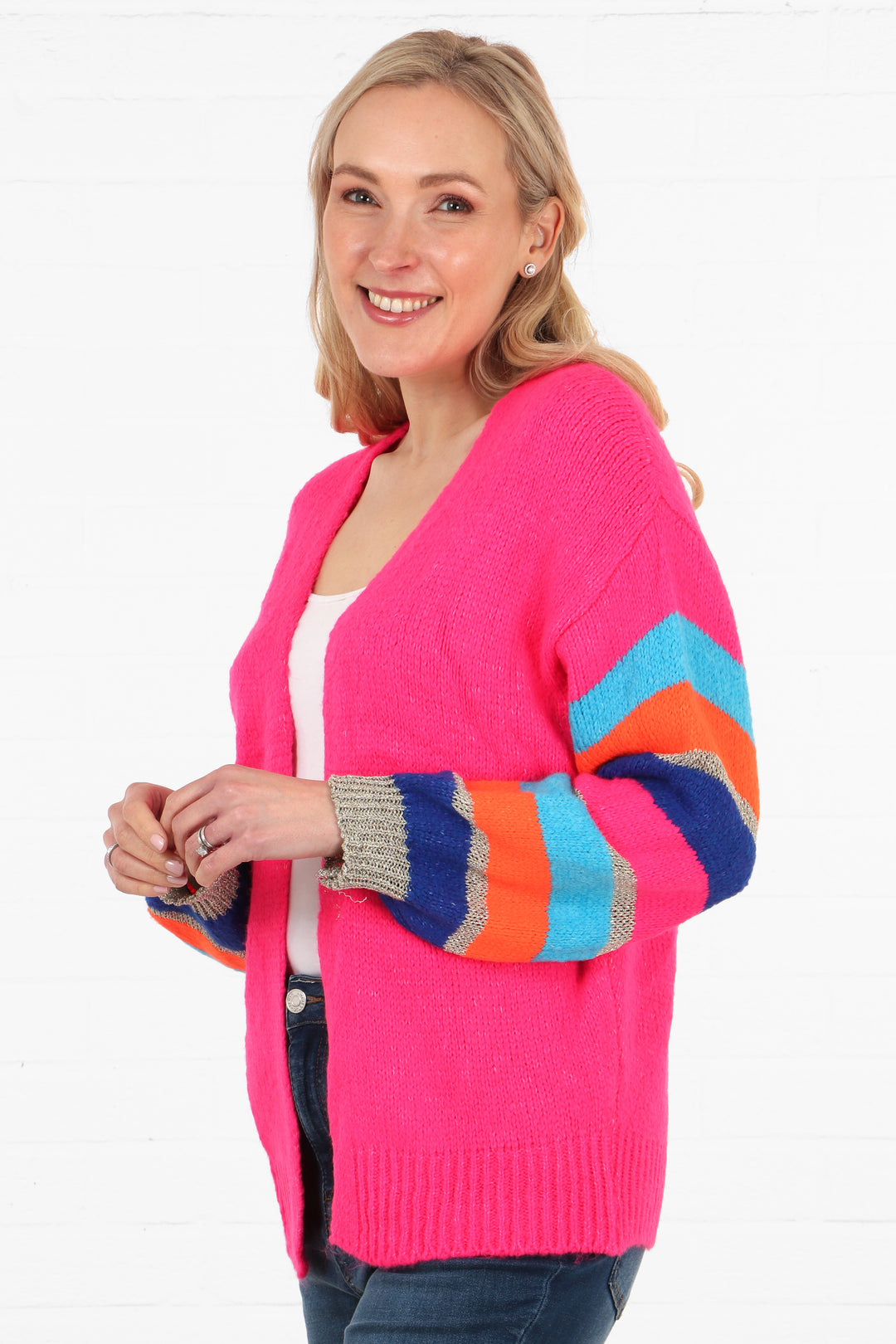 model wearing a bright pink cardigan with multi-coloured striped sleeves