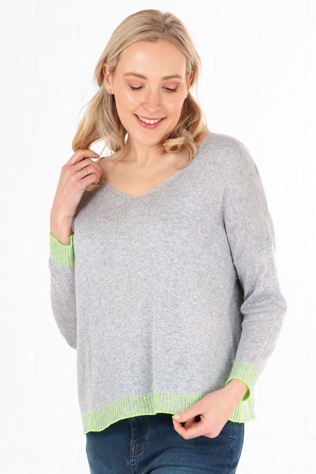 model wearing a v neck light grey cotton jumper with contasting lime green stitching on the edge and on the cuffs