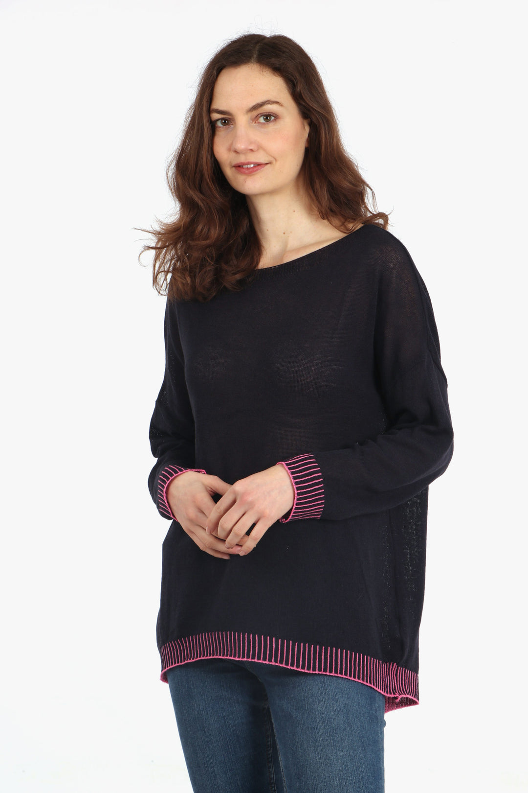 model wearing a navy blue long sleeved jumper with a pink contrast stitch trim around the cuffs and edge of the jumper