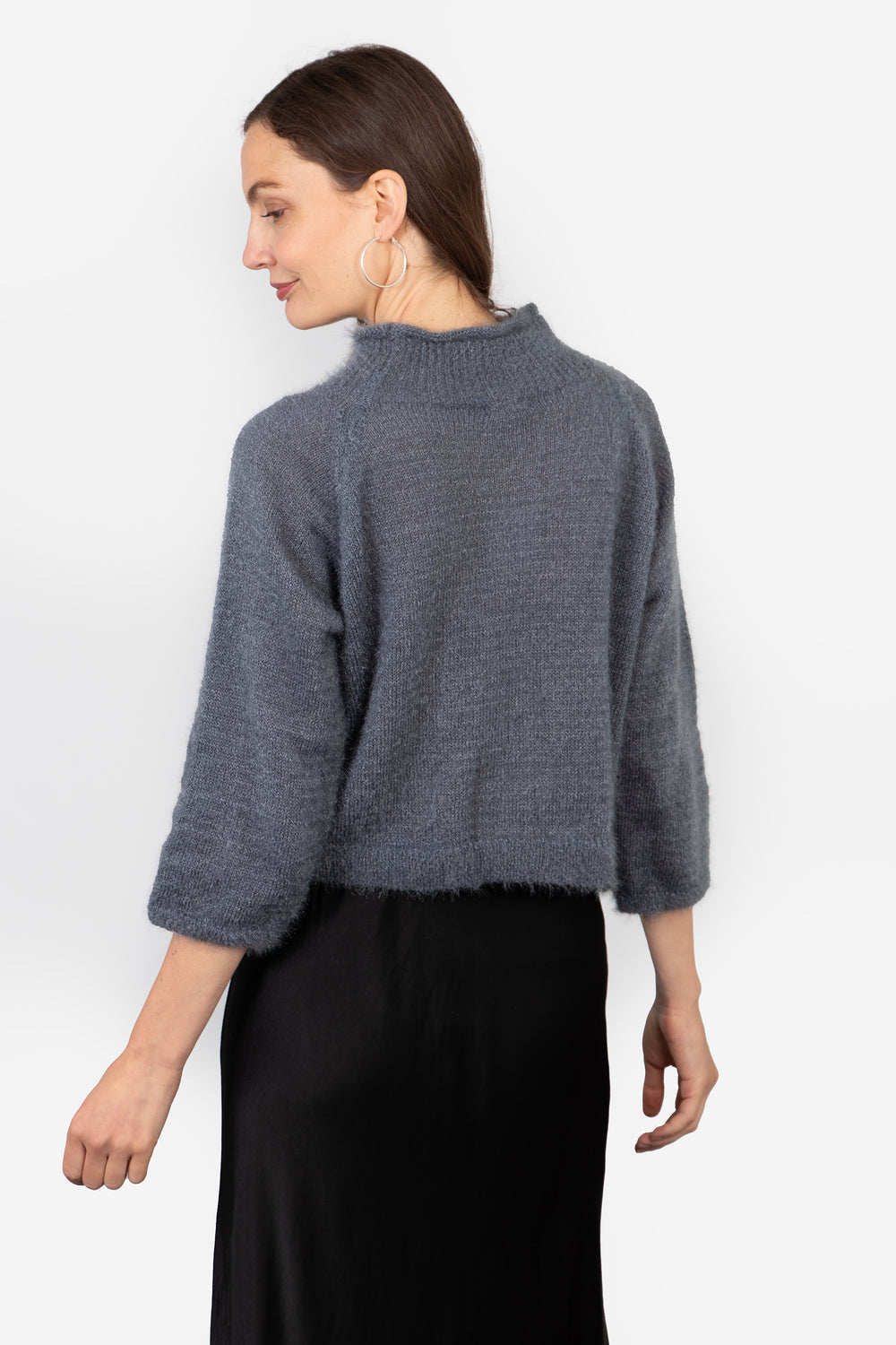 model showing the back of the jumper, the neck is high at the back and the design is plain