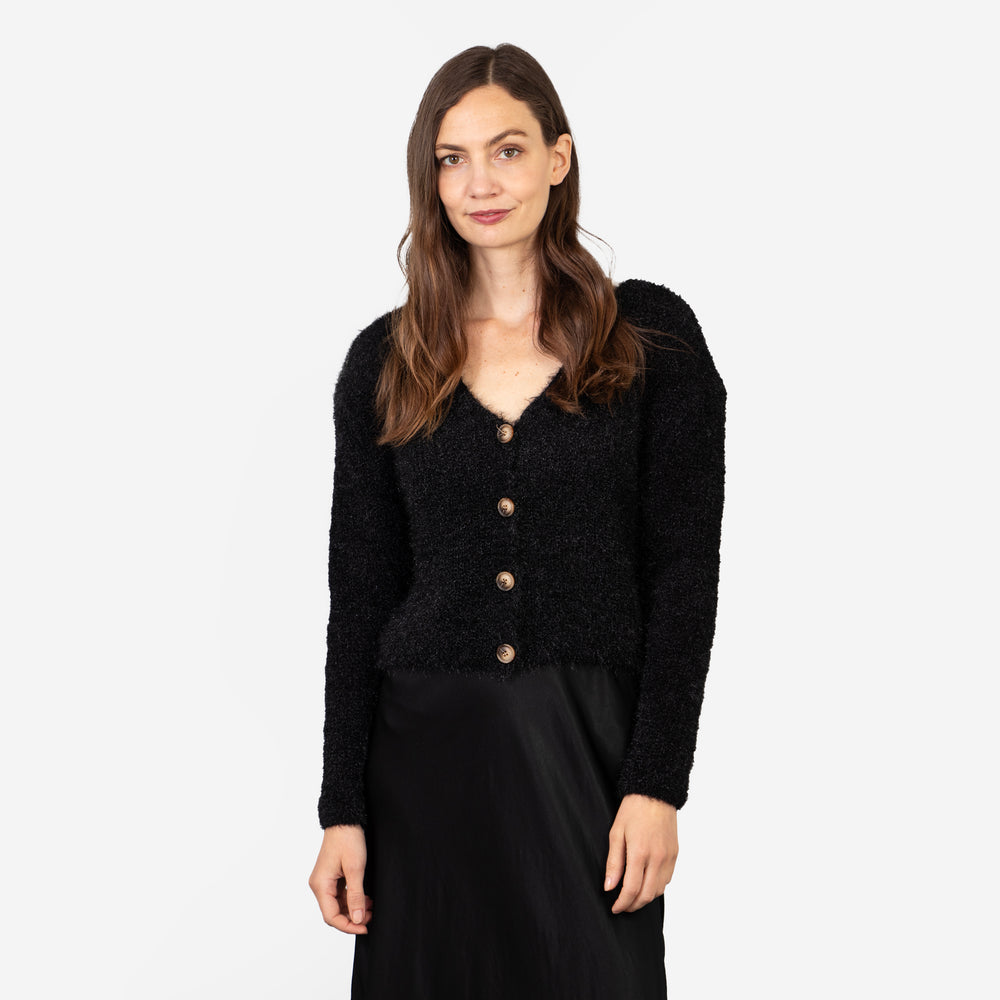 model wearing a black knit jumper with a v-neck and long sleeves