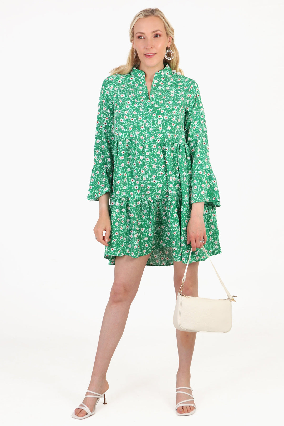 short green daisy floral mini dress being worn by a model, the model is wearing prominent hoop earrings, sandals and a leather bag showing how this dress can be styled for an occasion