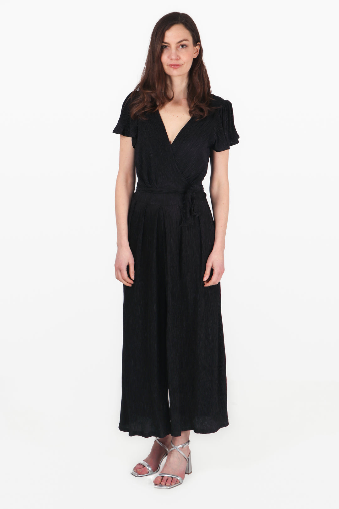 model wearing a black plisse jumpsuit with short angel sleeves and a v neck 1