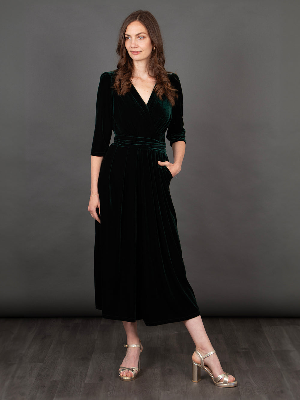 model wearing a cropped green velvet jumpsuit with a v-neck and pockets