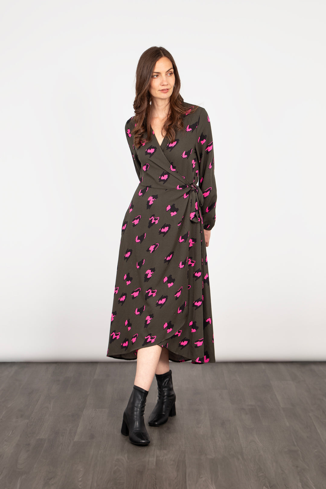 model wearing a khaki and pink leopard print midi wrap dress, the dress has long sleeves and a v-neck