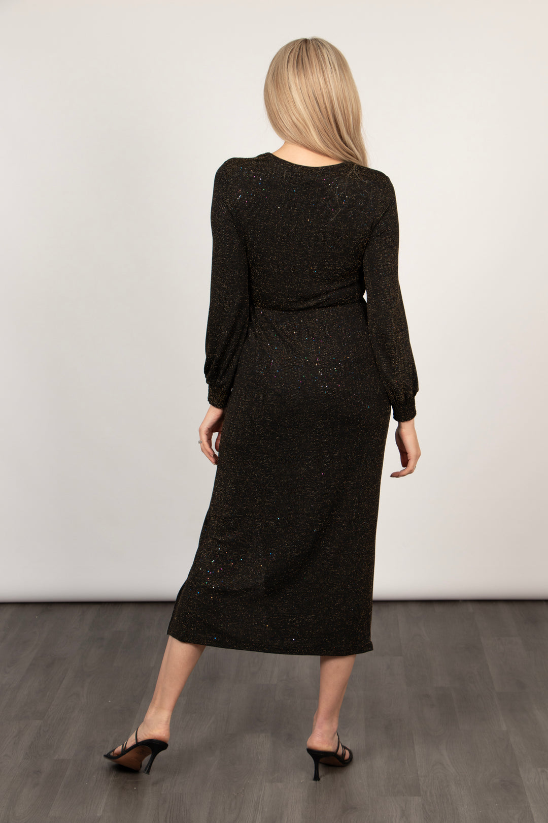 model showing the back of the dress, it is midi length and had an all over bronze sparkle