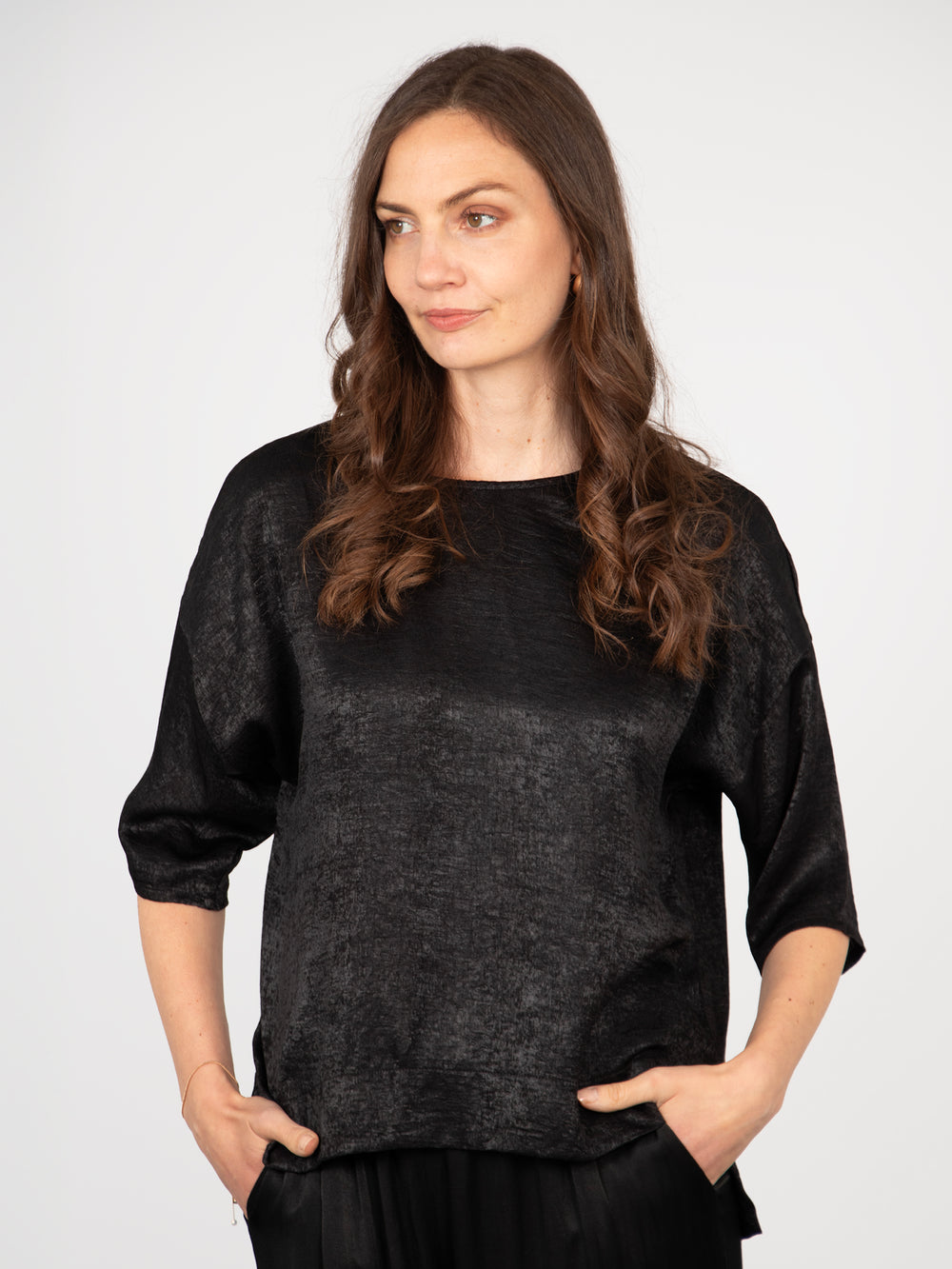 model wearing a black metallic cropped sleeve box top with a dipped hem and round neck
