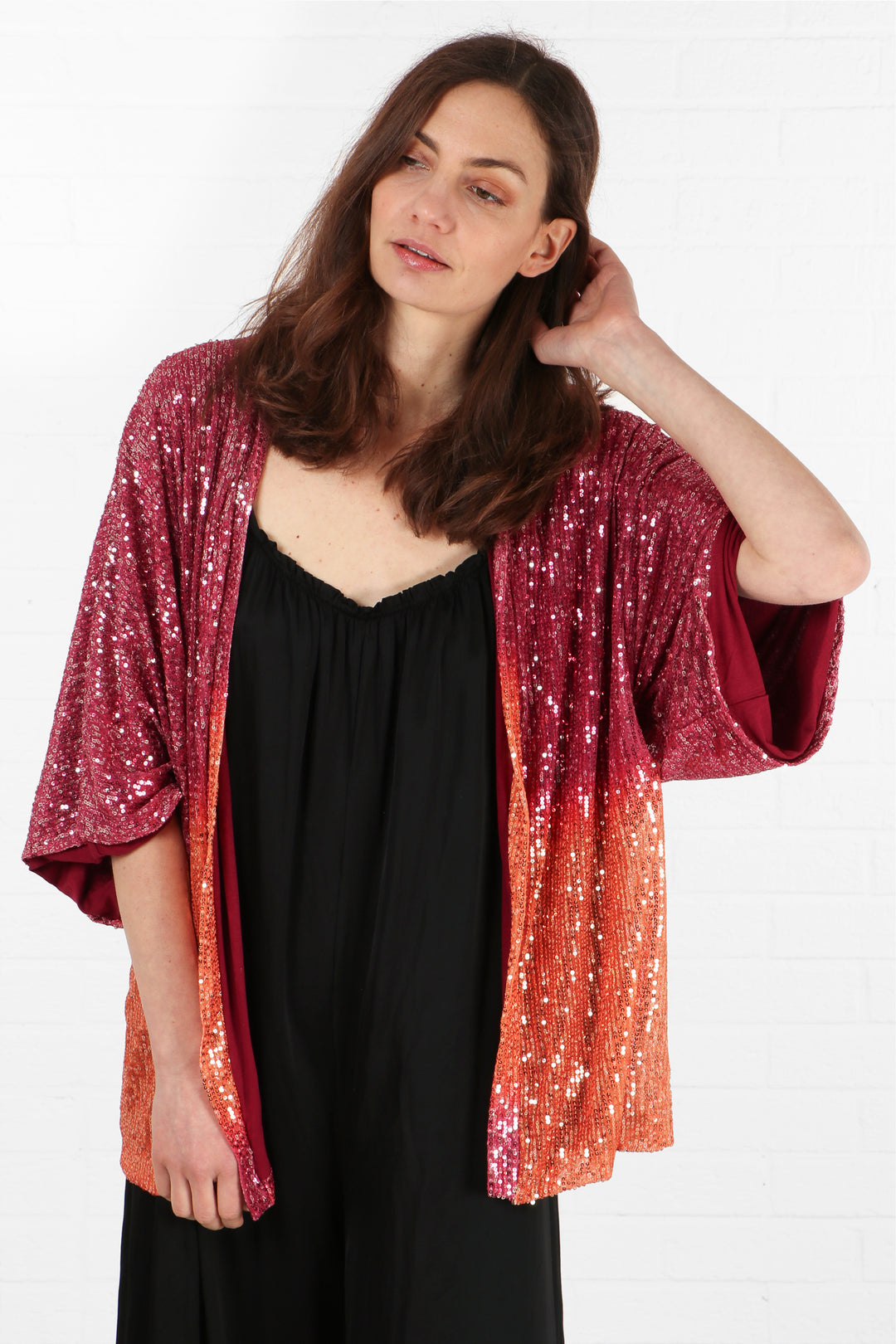 model wearing a pink and coral open front sparkly sequin short kimono jacket