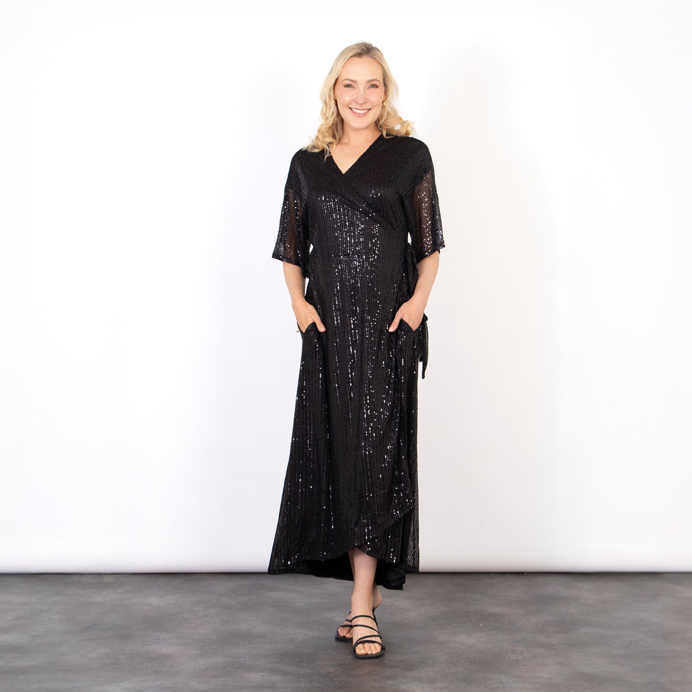 model wearing a black midi length dipped hem sparkly sequinned wrap dress with a v-neck and waist tie fastening