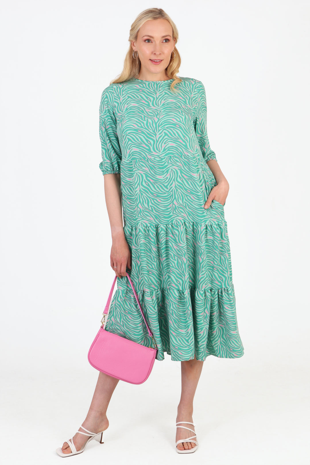 model wearing a tiered midi dress with an all over pattern of zebra print and lightning bolts, the dress is mint green with pink accents