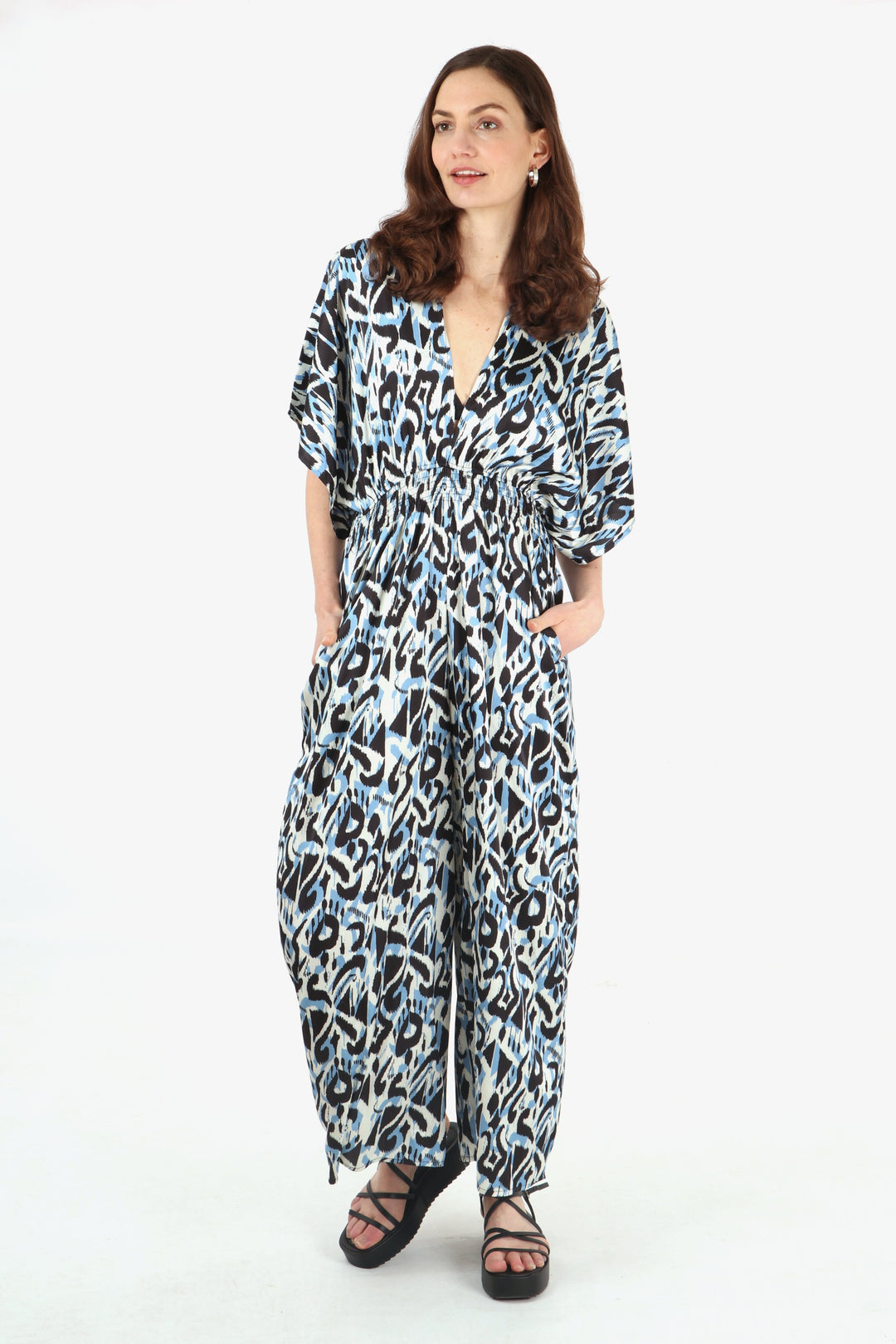 model wearing a blue ikat pattern wide leg jumpsuit with plunging v neck and short angel sleeves