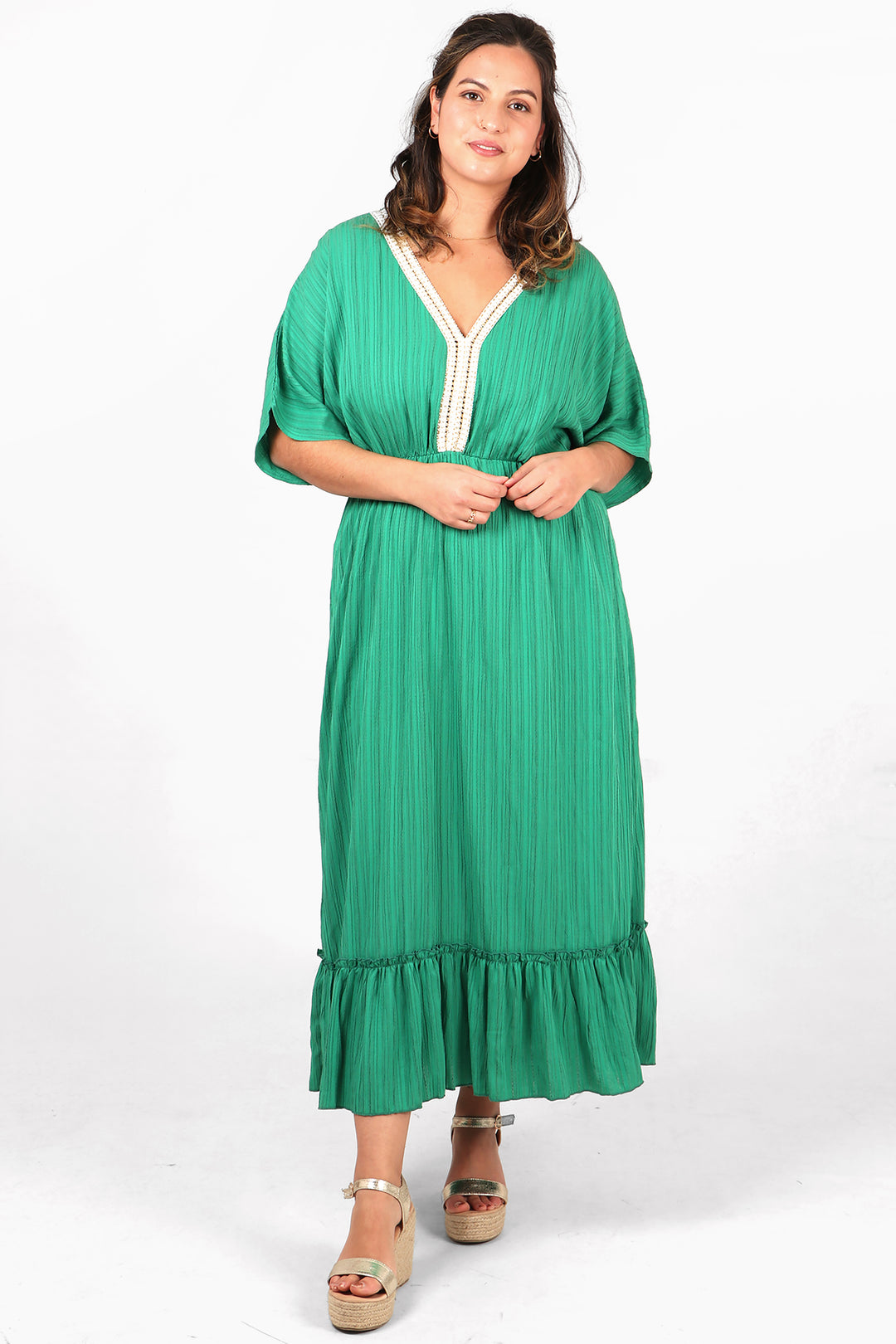 model wearing a midi length 3/4 sleeve green dress with a v neck, there is white and gold robe trim around the v neck