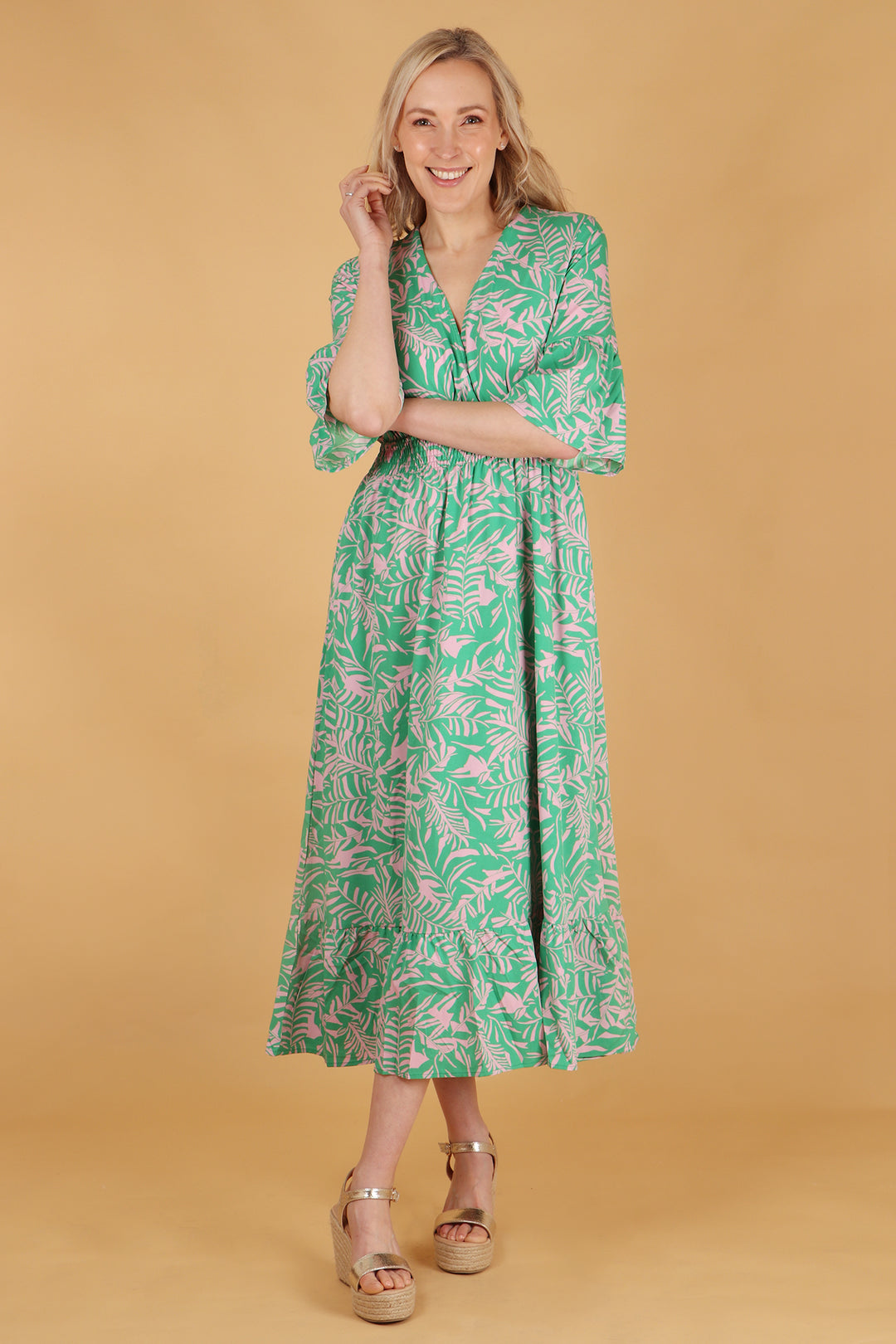 model wearing a green and pink tropical leaf print maxi dress with 3/4 sleeves and a shirred waist