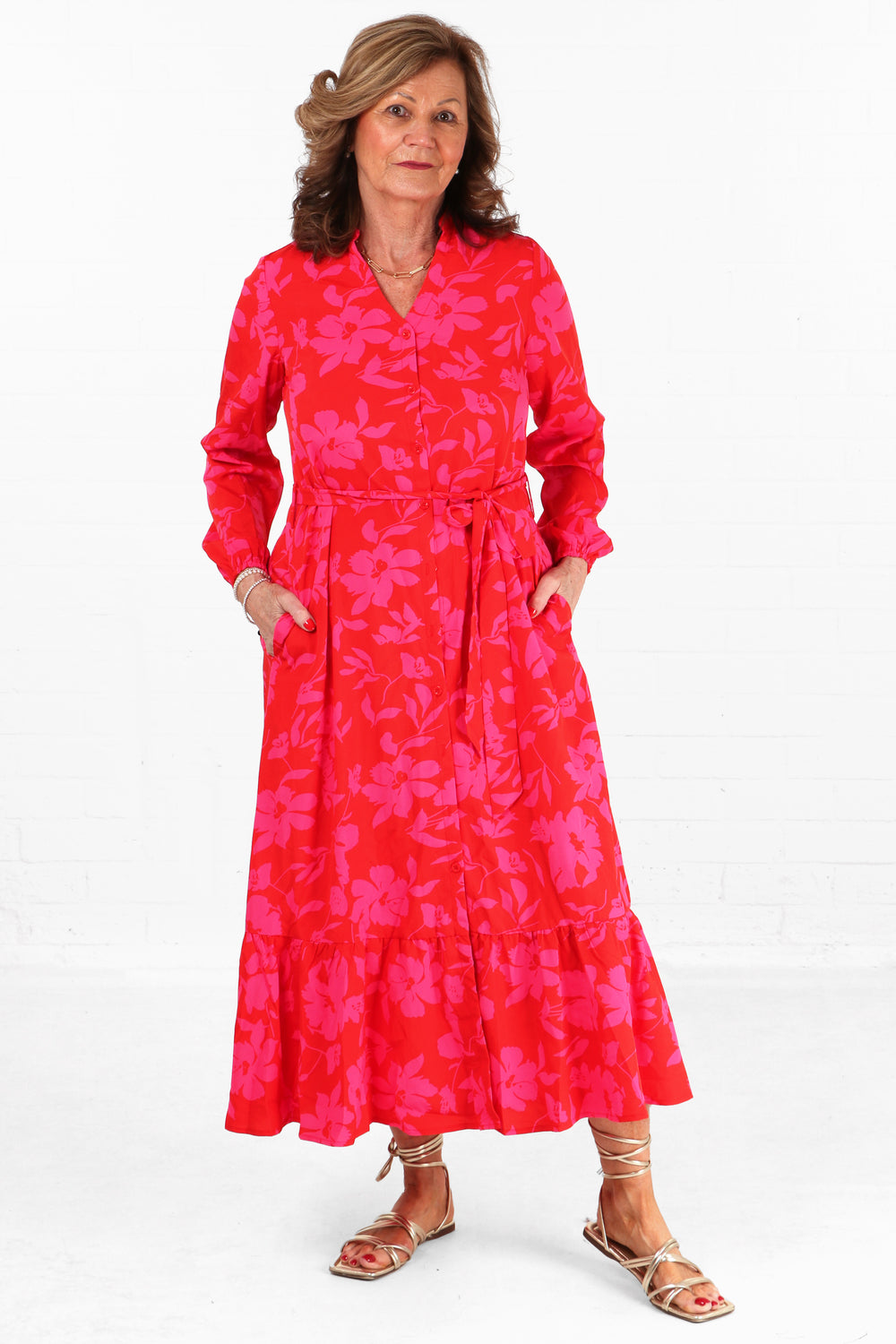 model wearing a midaxi length red floral print shirt dress with long sleeves and belt tie waist