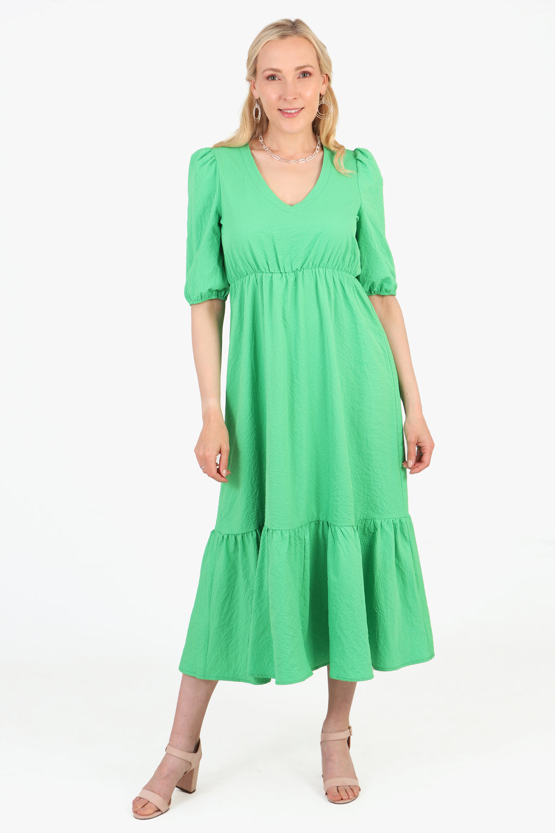 model wearing a plain green tiered midaxi dress, the dress has a v necl and elbow length sleeves
