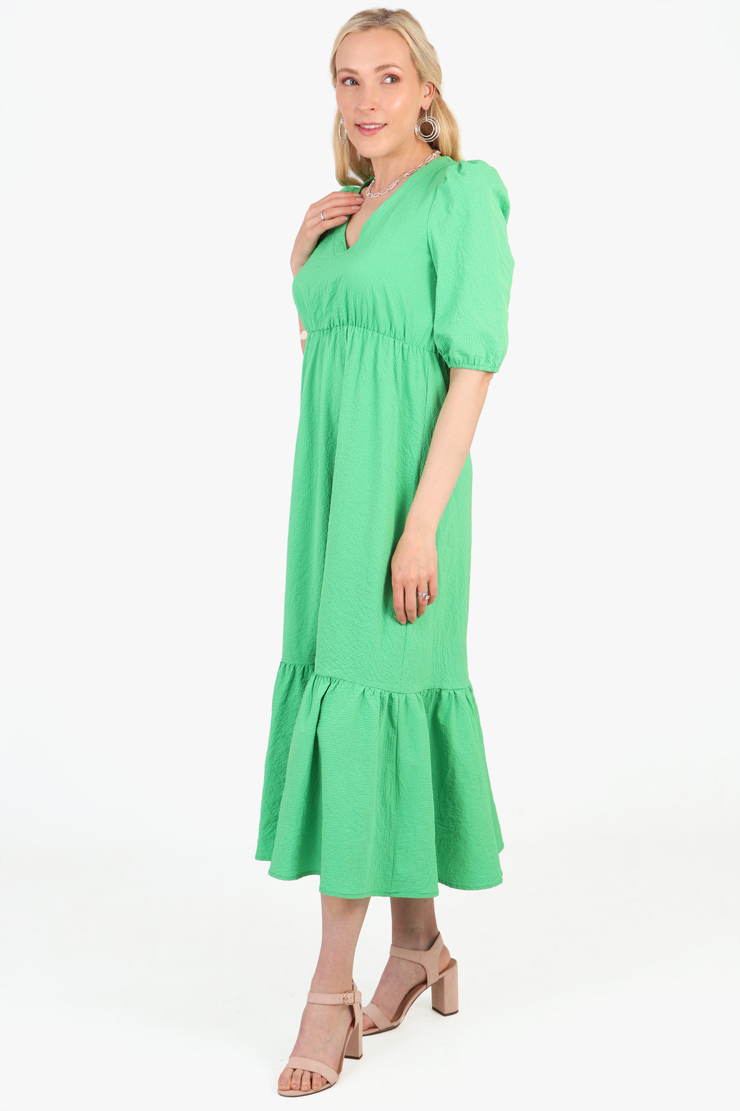 model showing a side view of the green tiered dress, showing the elbow length sleeves and v-neck