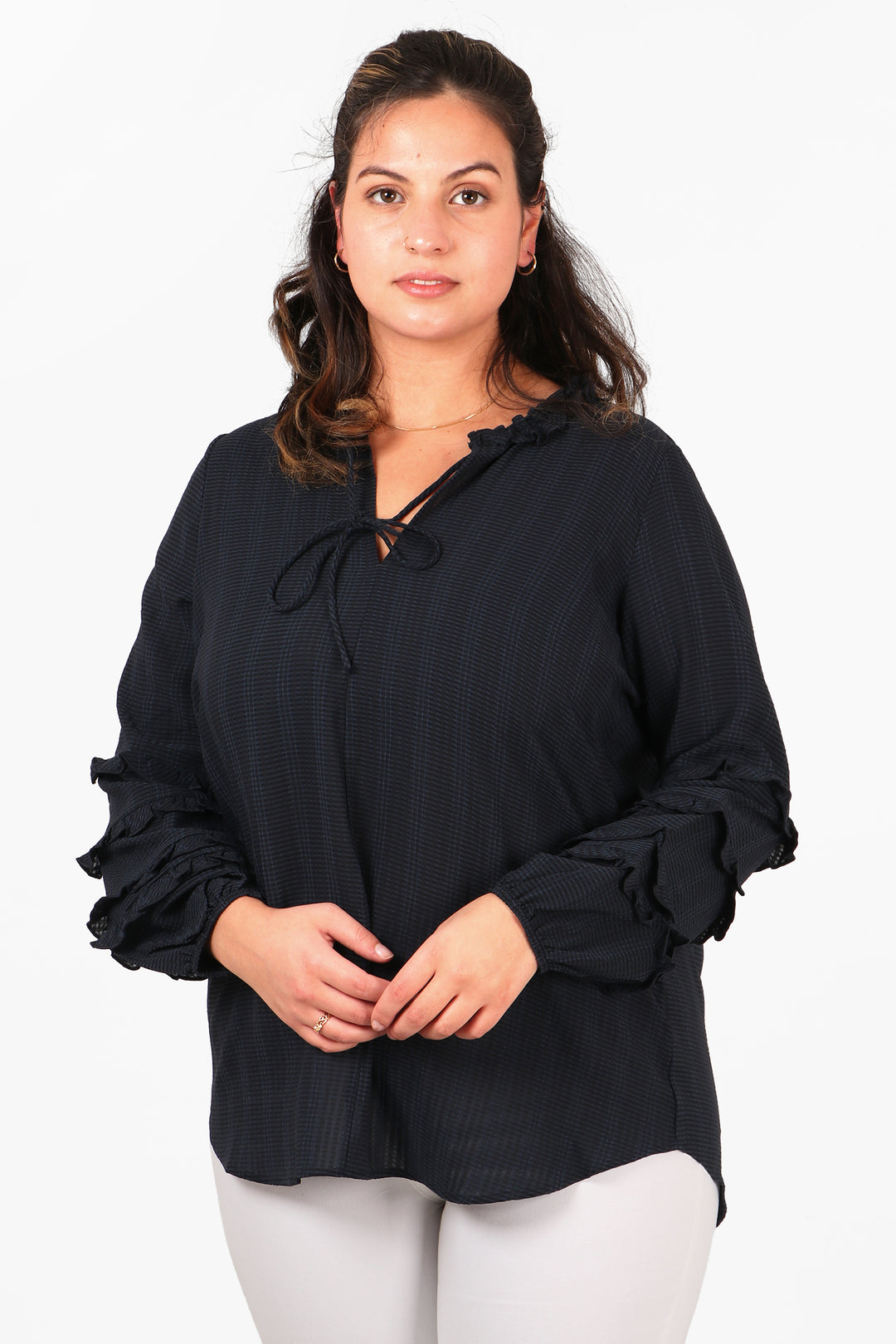model wearing a navy blue long sleeved shirt with frill sleeves and a grandad collar