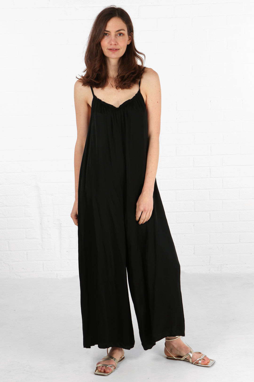 model wearing an black wide leg jumpsuit with a v neck and spaghetti straps
