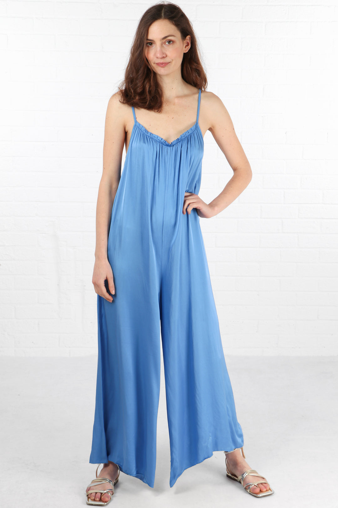 model wearing an azure blue wide leg jumpsuit with a v neck and spaghetti straps
