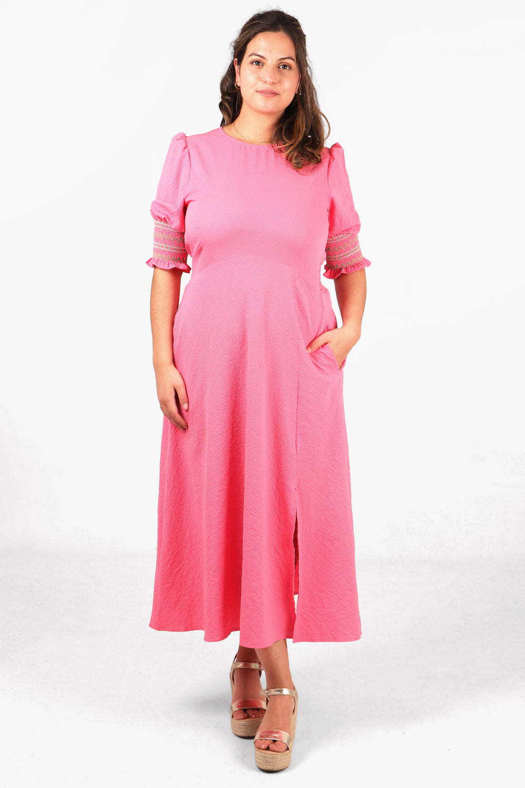 model wearing a pink tea dress with 3/4 elbow length embroidered sleeves, front split and round neck